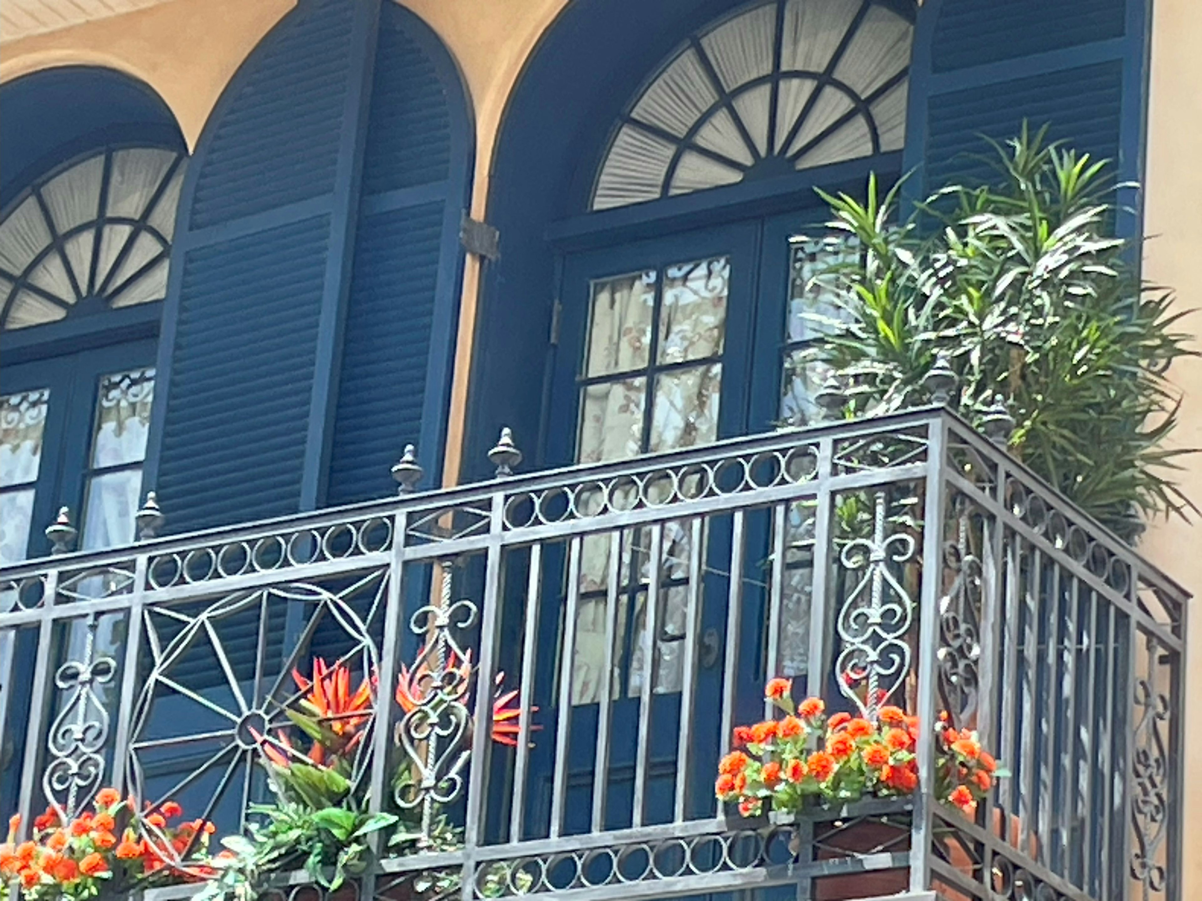 Exterior de un edificio con ventanas azules y un balcón adornado con flores