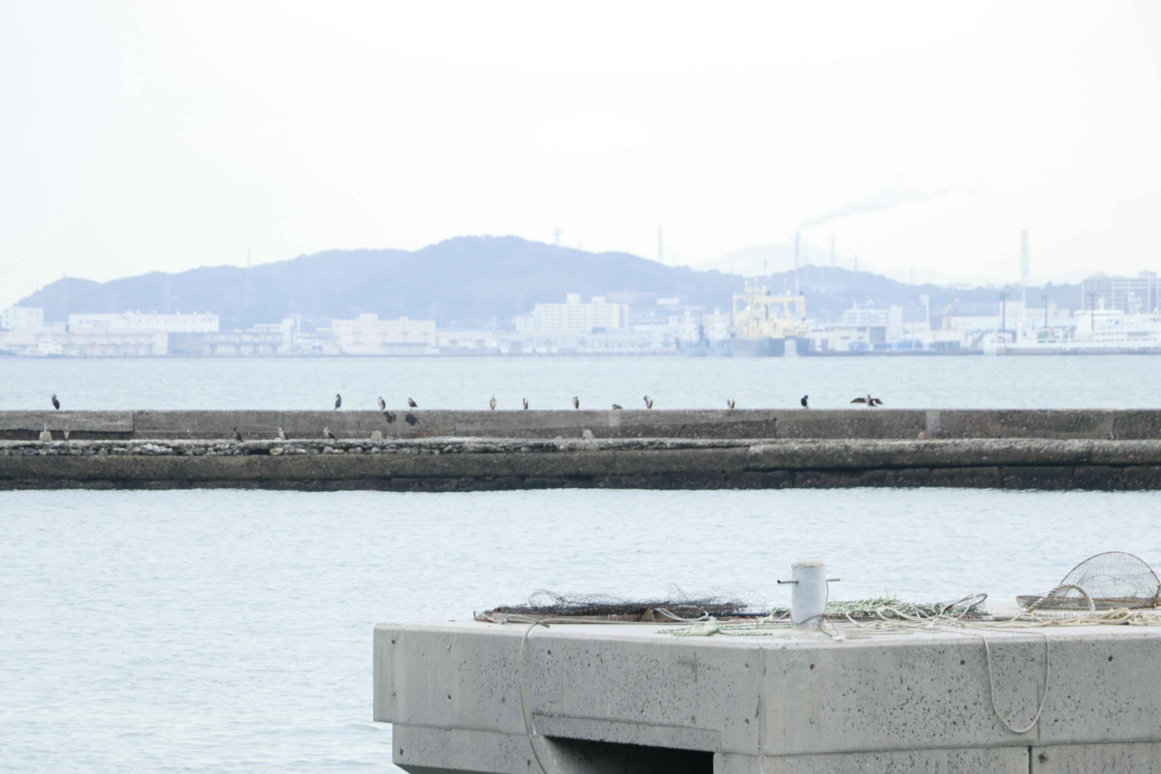 View of coastline and breakwater with distant hills