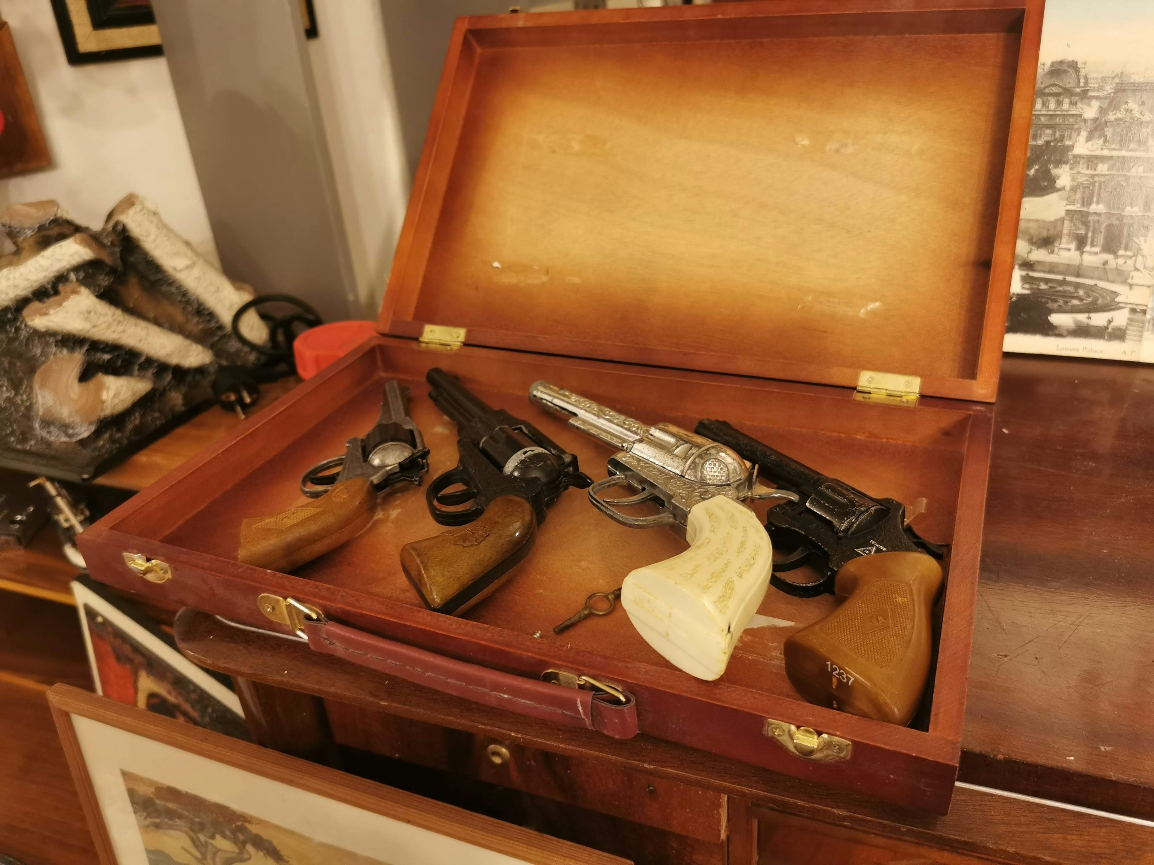 A wooden case containing several pistols and handguns