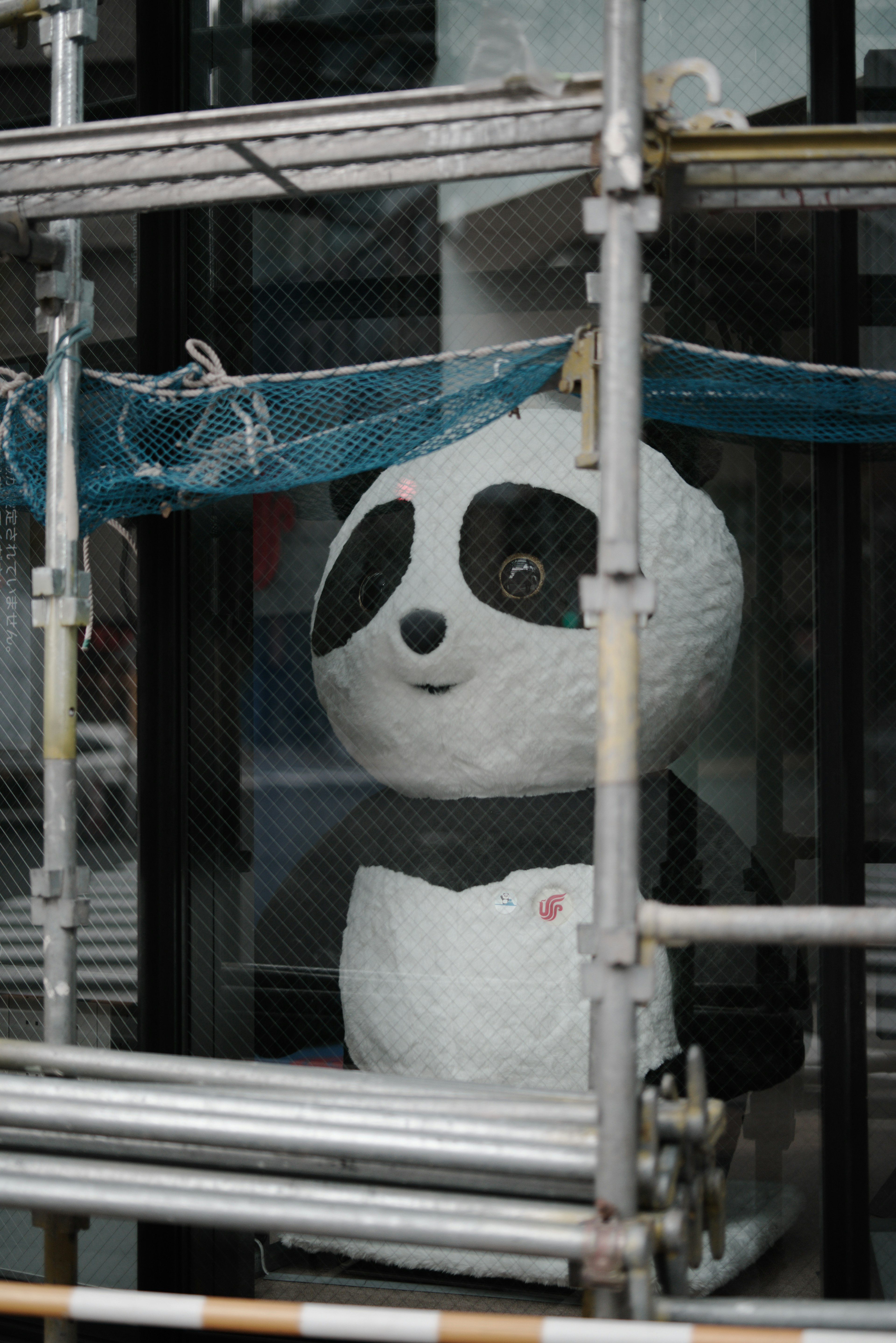 Mascota panda visible a través de un andamiaje de construcción