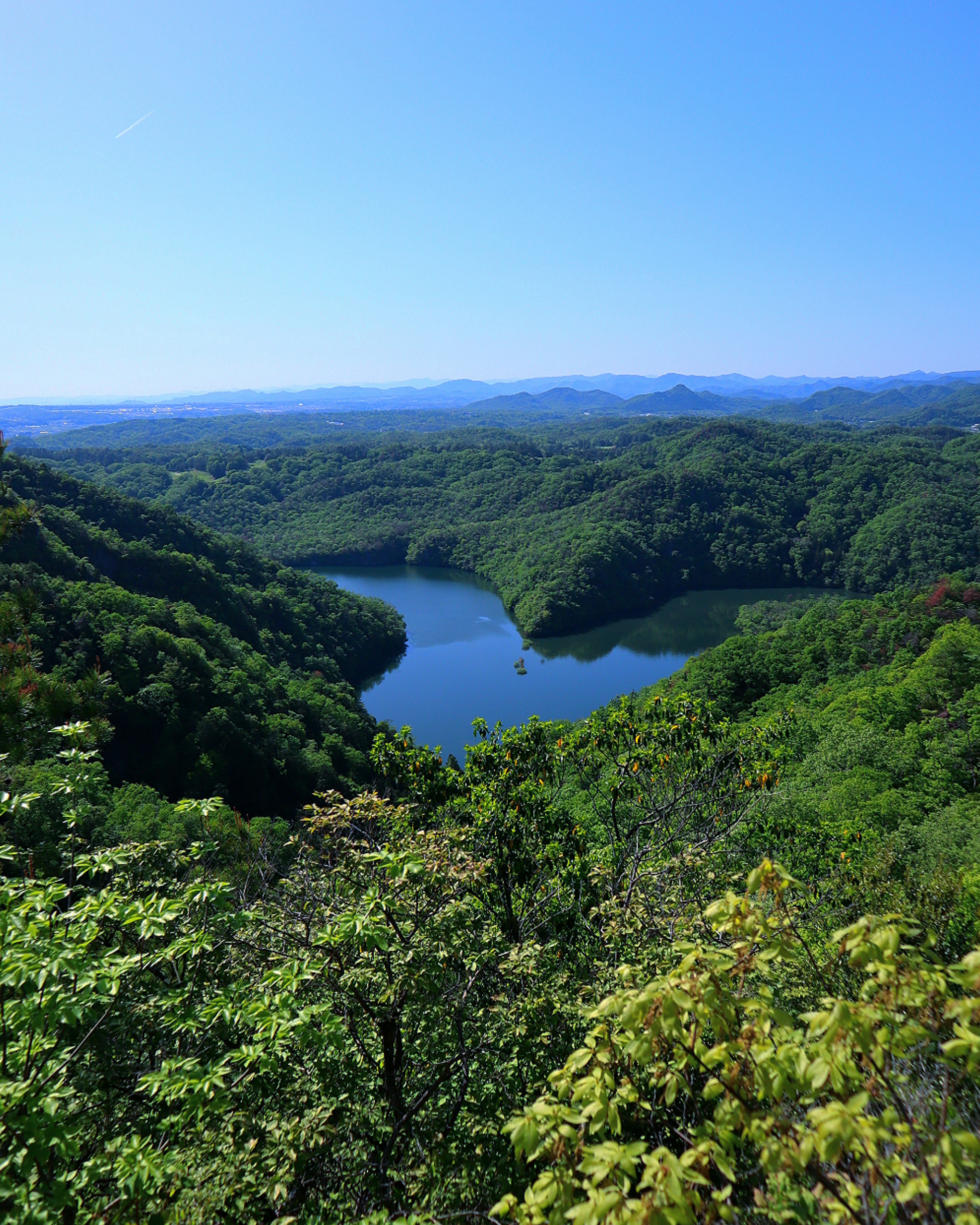 Lago rodeado de colinas verdes bajo un cielo azul claro