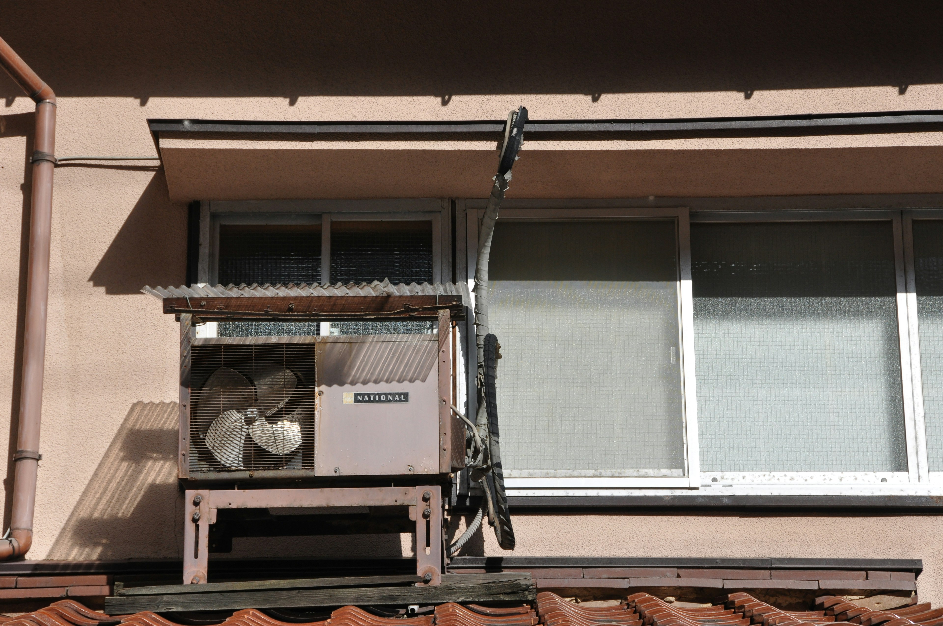 Klimaanlage, die außerhalb eines Fensters mit umgebenden Strukturen installiert ist