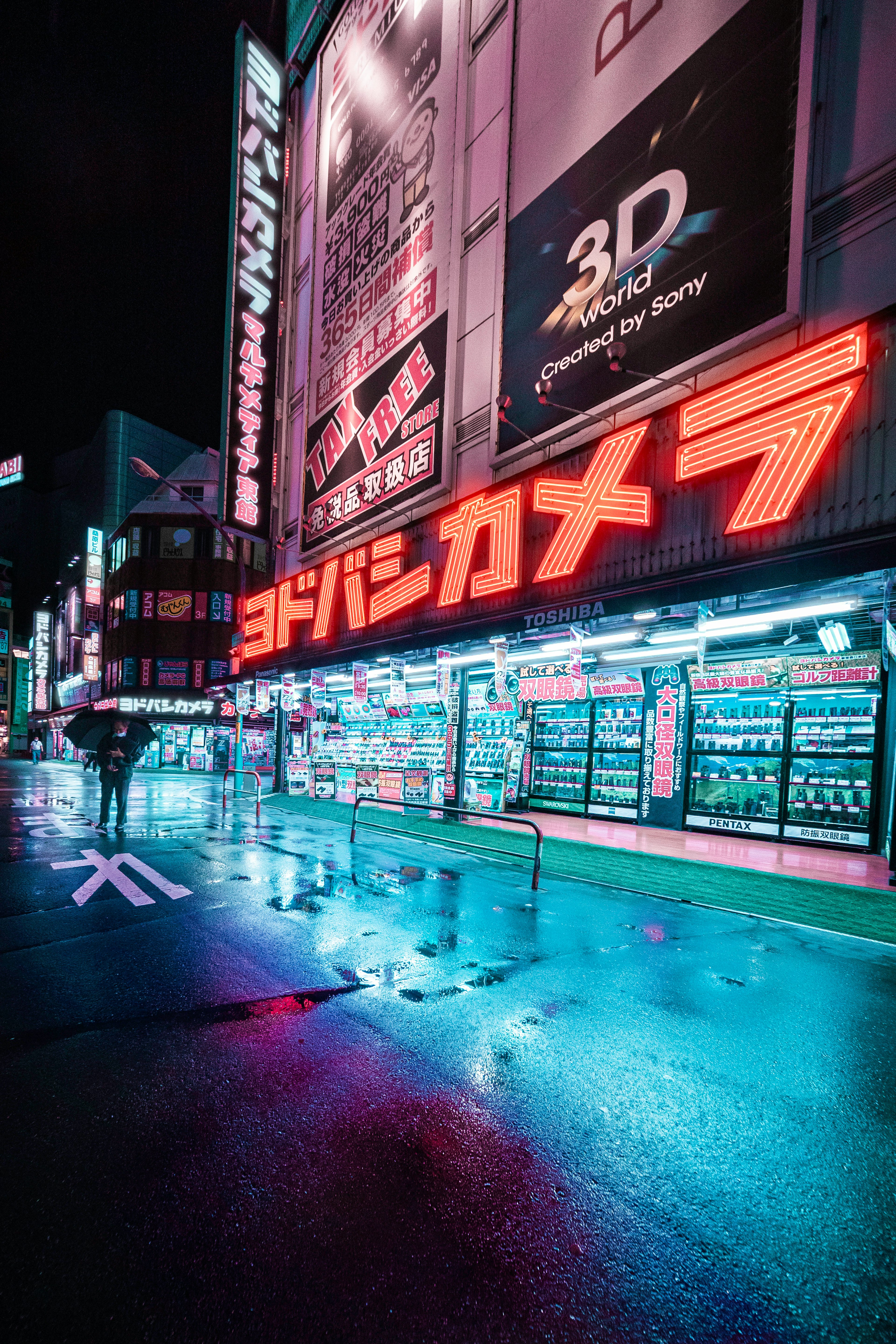 夜の街並みに映えるヨドバシカメラの店舗 neon signと反射する水たまり