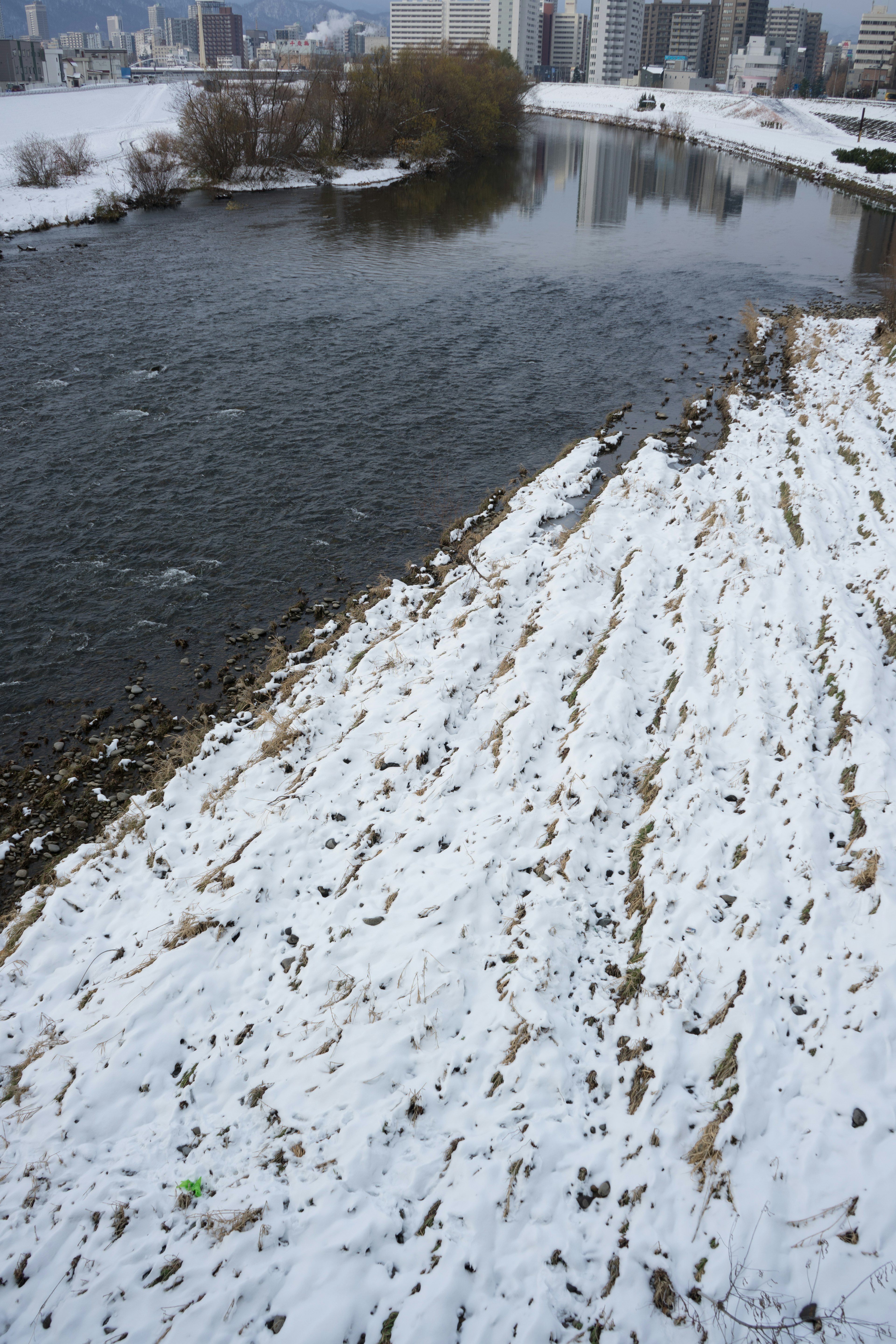 Snow-covered riverbank and flowing water landscape