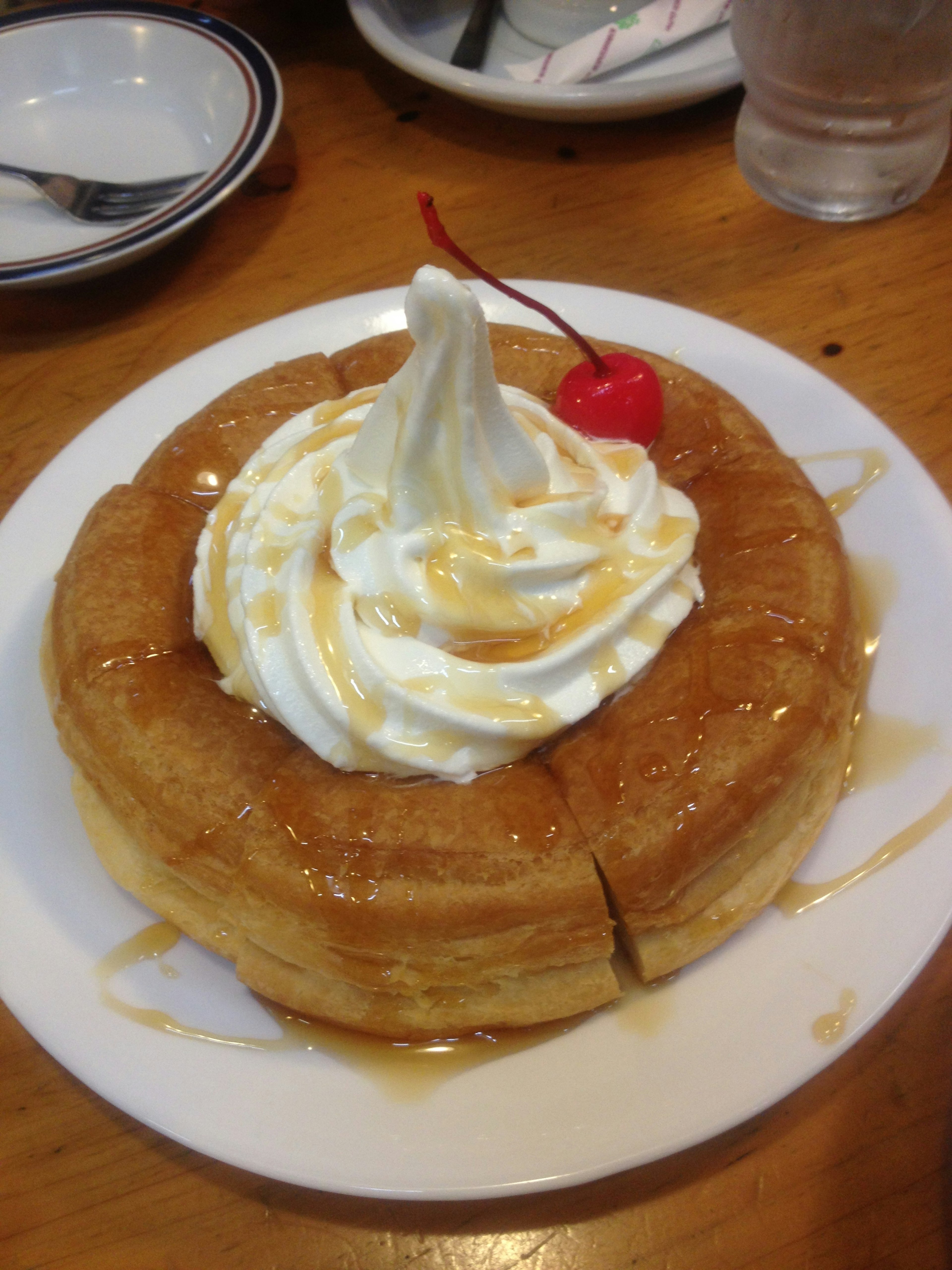 Tostada francesa cubierta con crema batida y una cereza