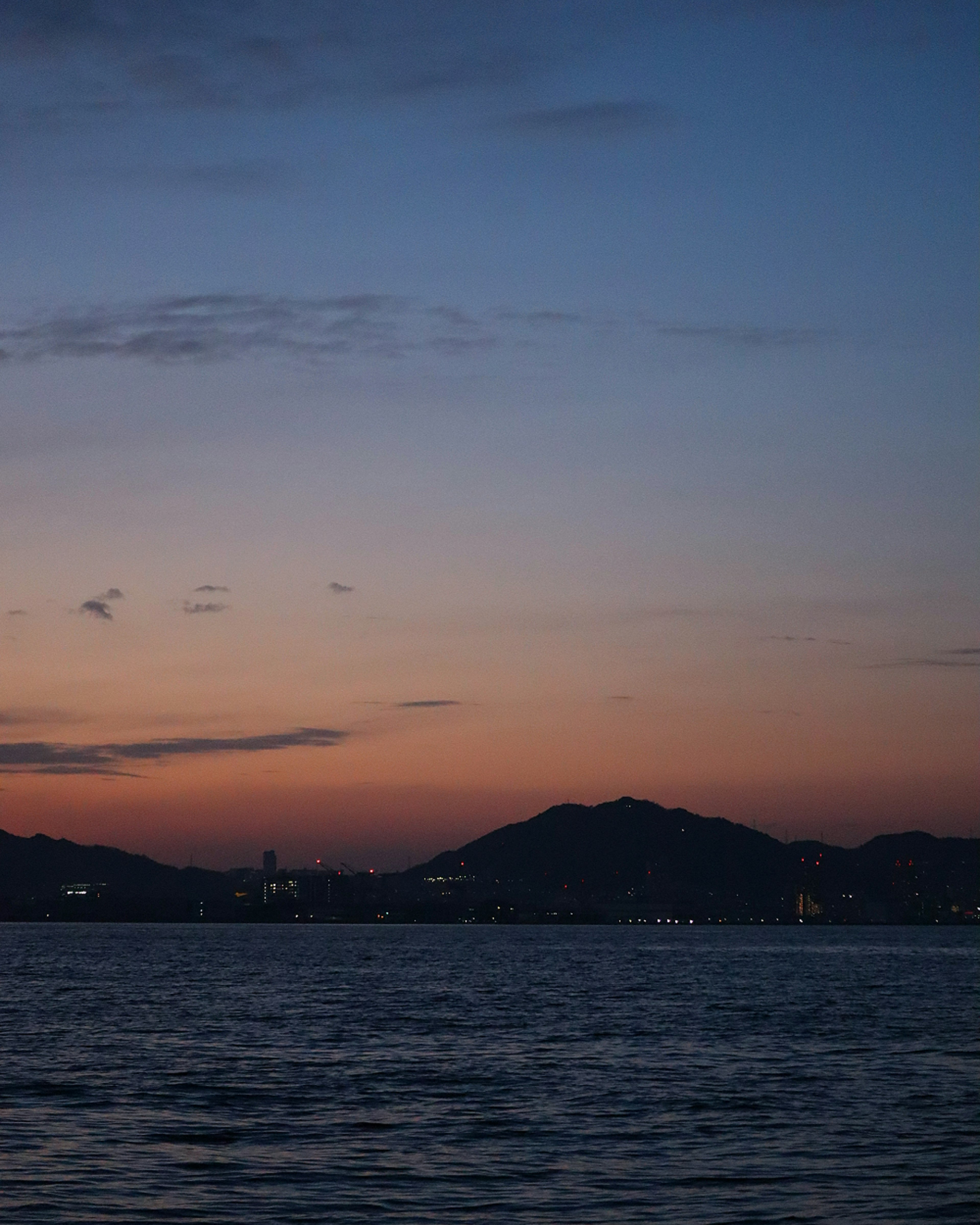 Sunset over the sea with mountains silhouette and gradient sky colors