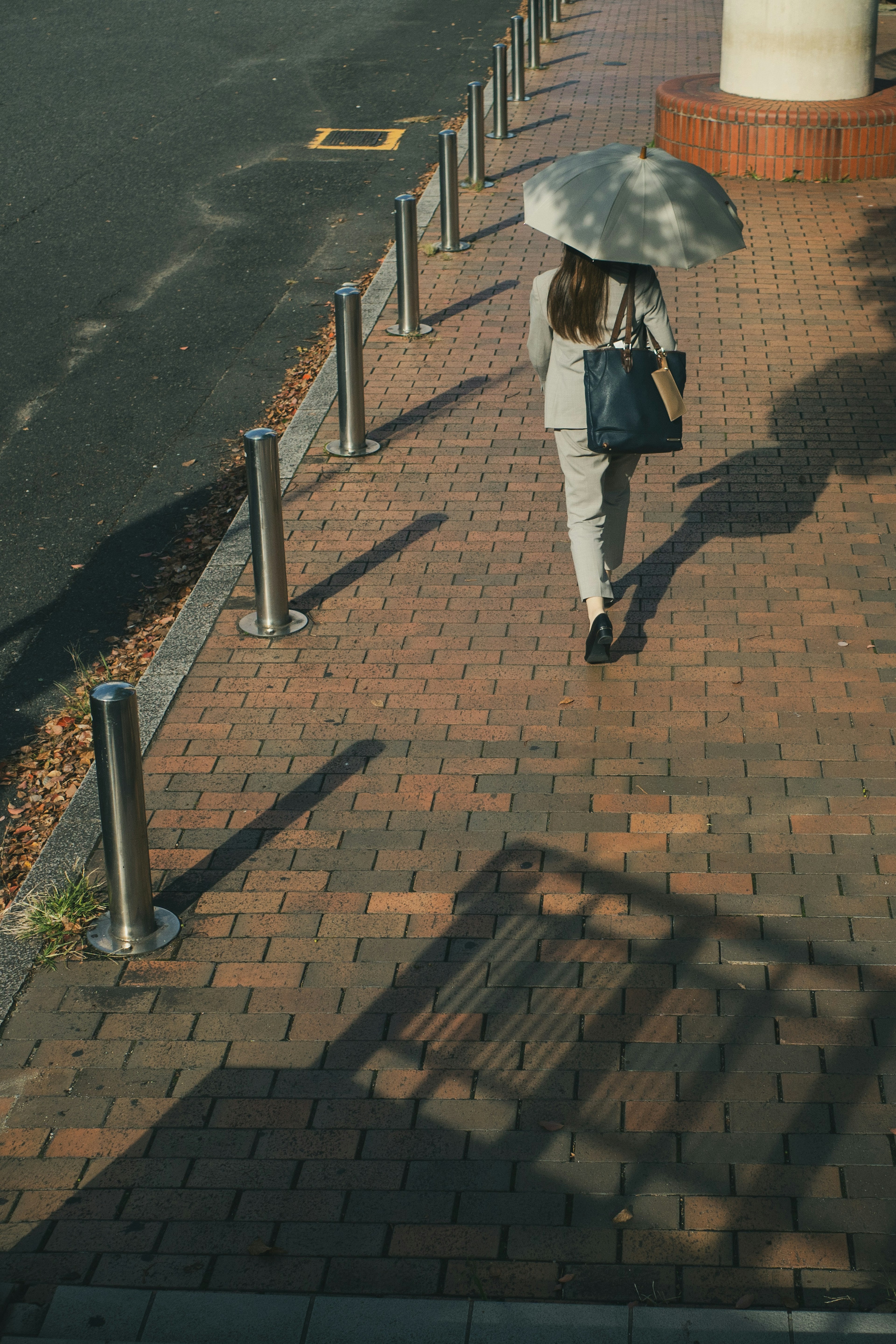 A woman walking on a paved path holding an umbrella