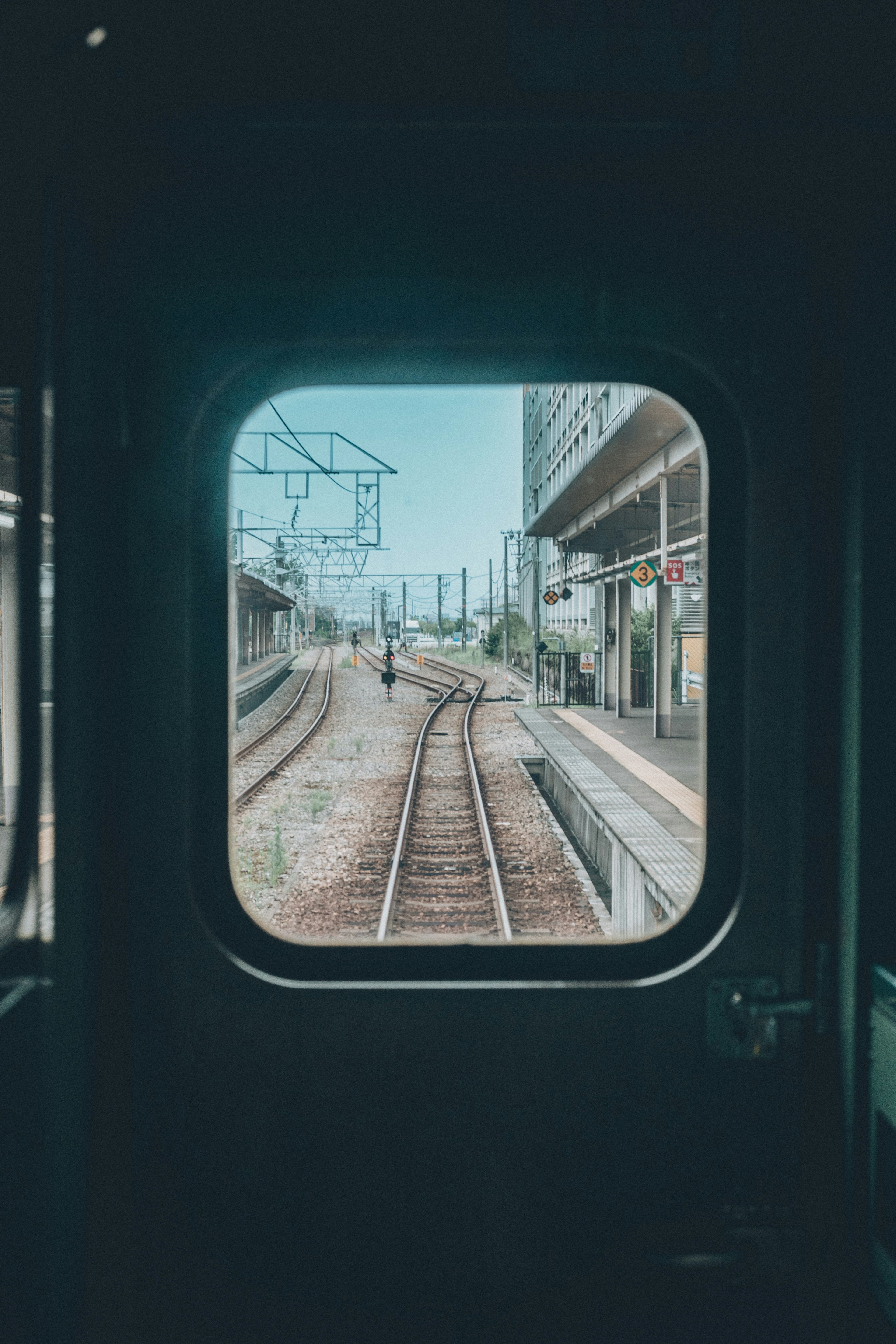 Vista da un finestrino di treno che mostra binari e strutture della stazione