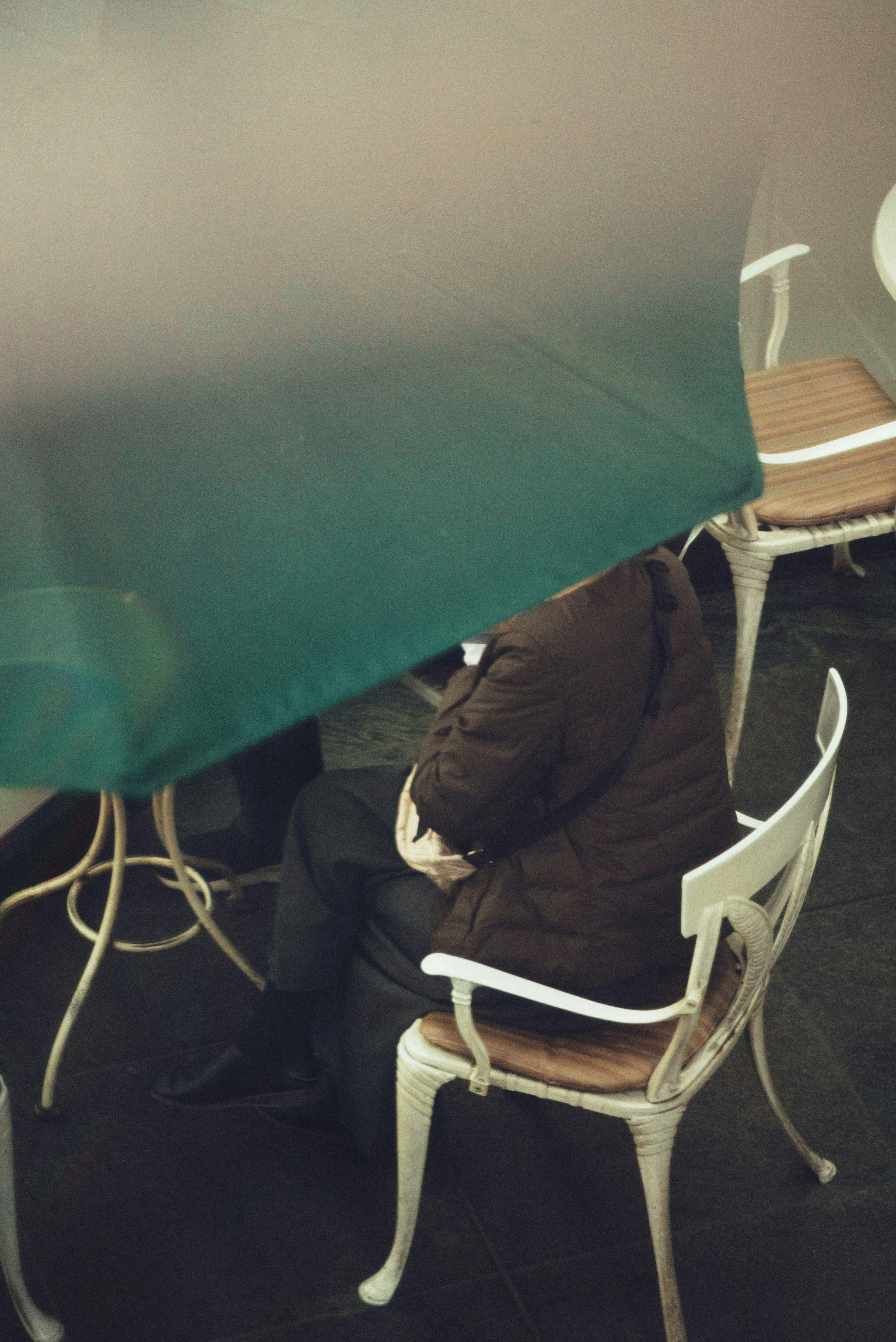 Une personne assise sous un auvent vert avec seulement le haut de son corps visible dans un café