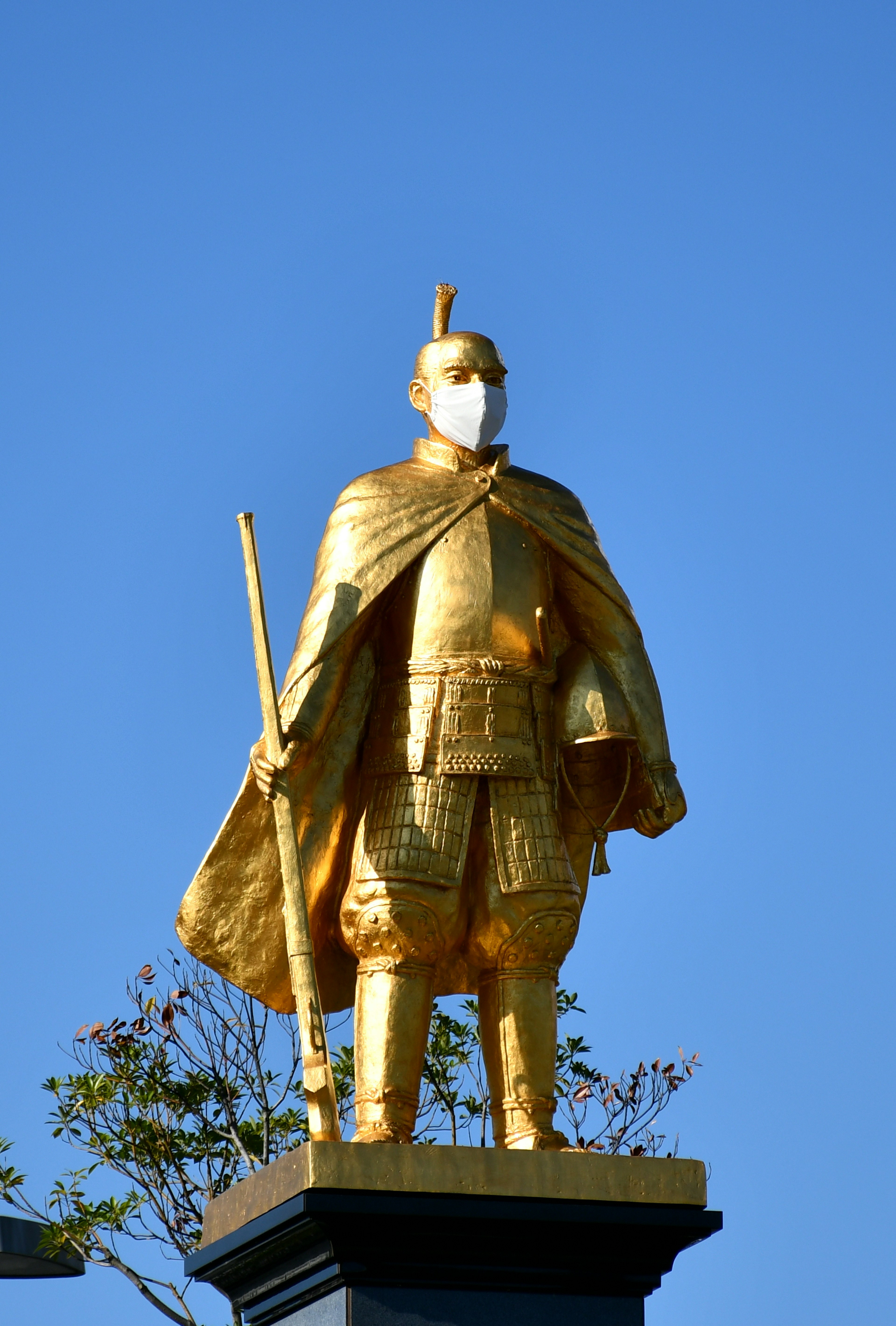 Goldene Kriegerstatue steht unter einem blauen Himmel