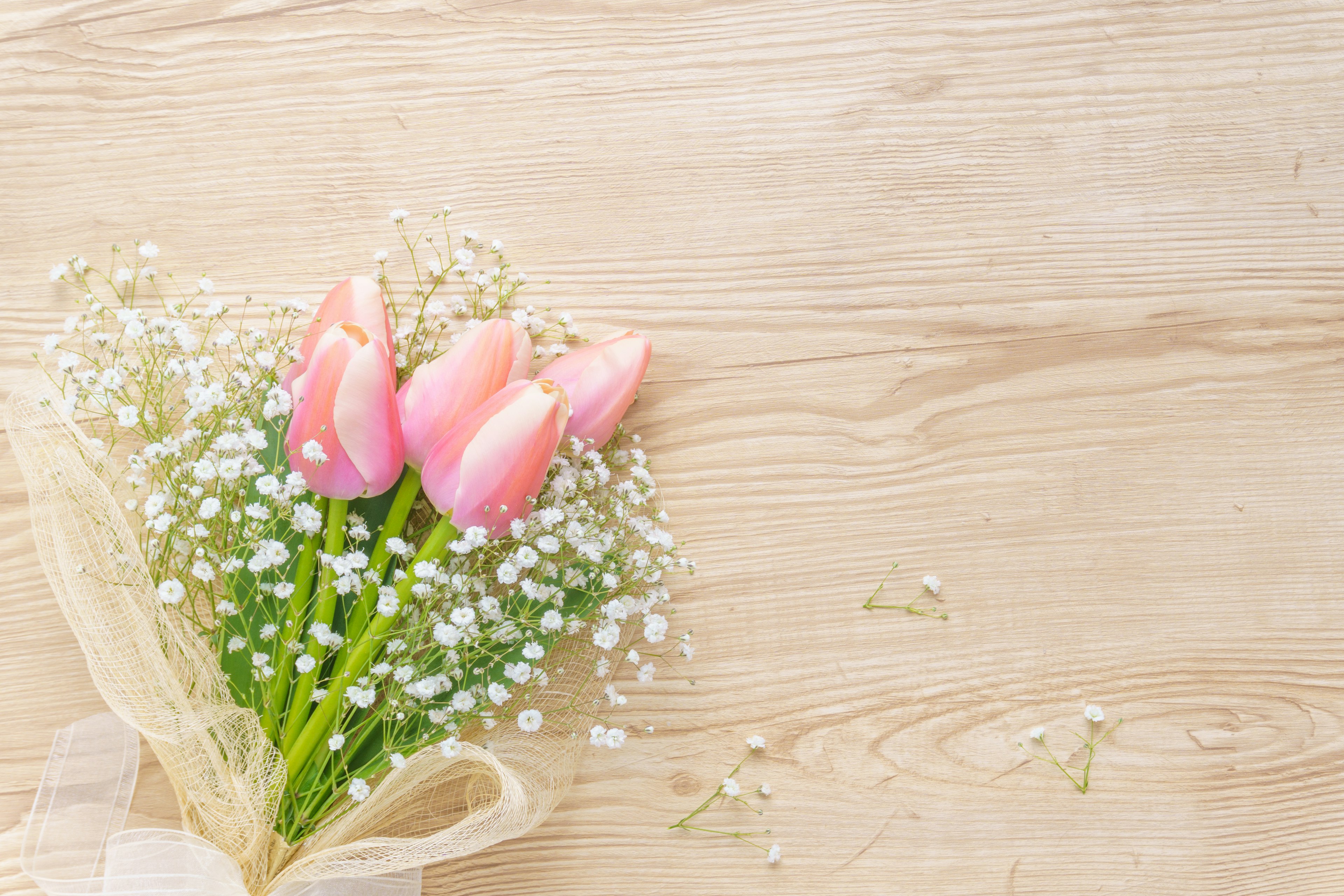 A bouquet of pale pink tulips and baby's breath on a wooden table