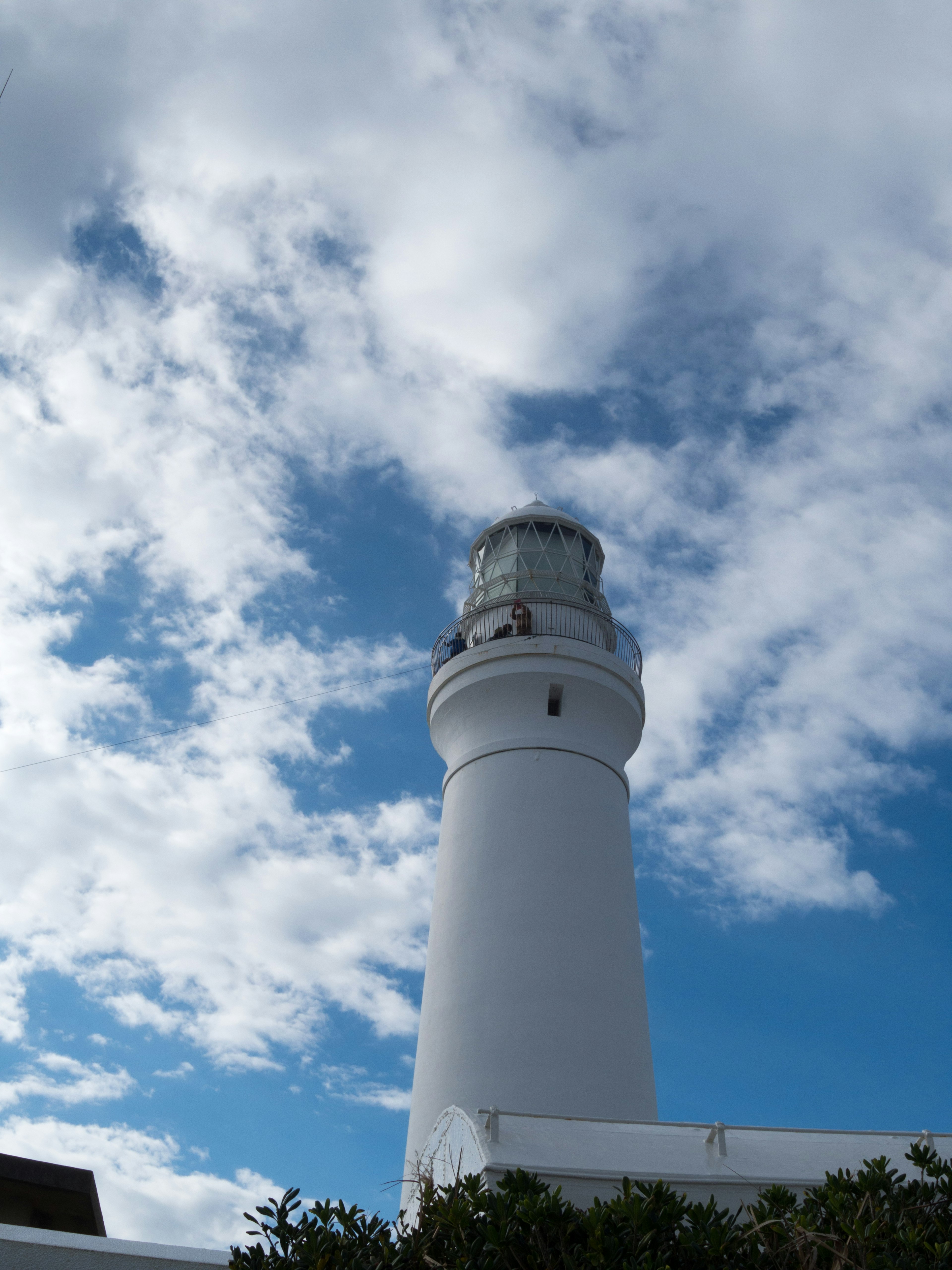 A white lighthouse towering under a blue sky