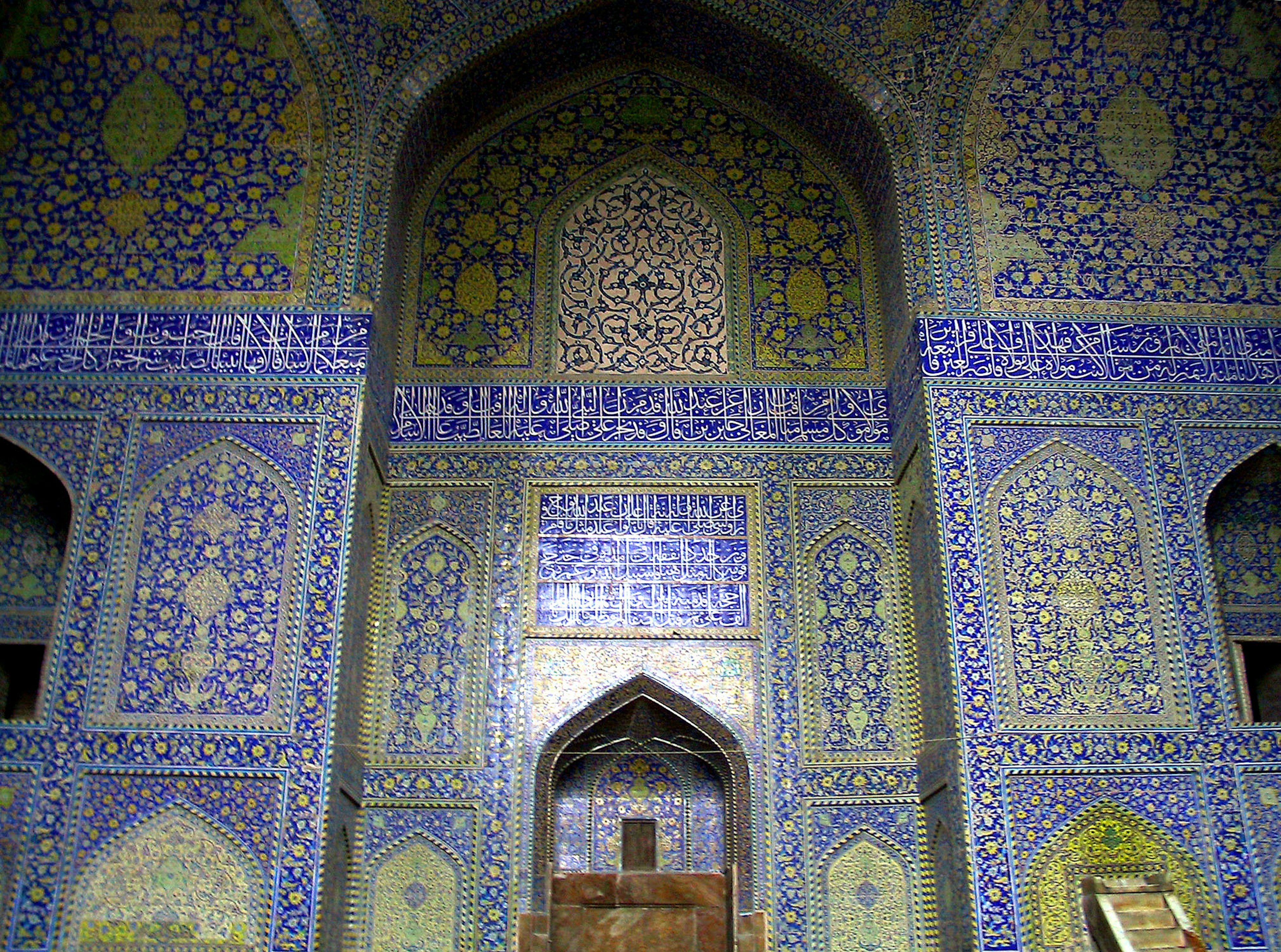 Vista interior de una pared con intrincadas decoraciones de azulejos que presentan tonos azules y verdes