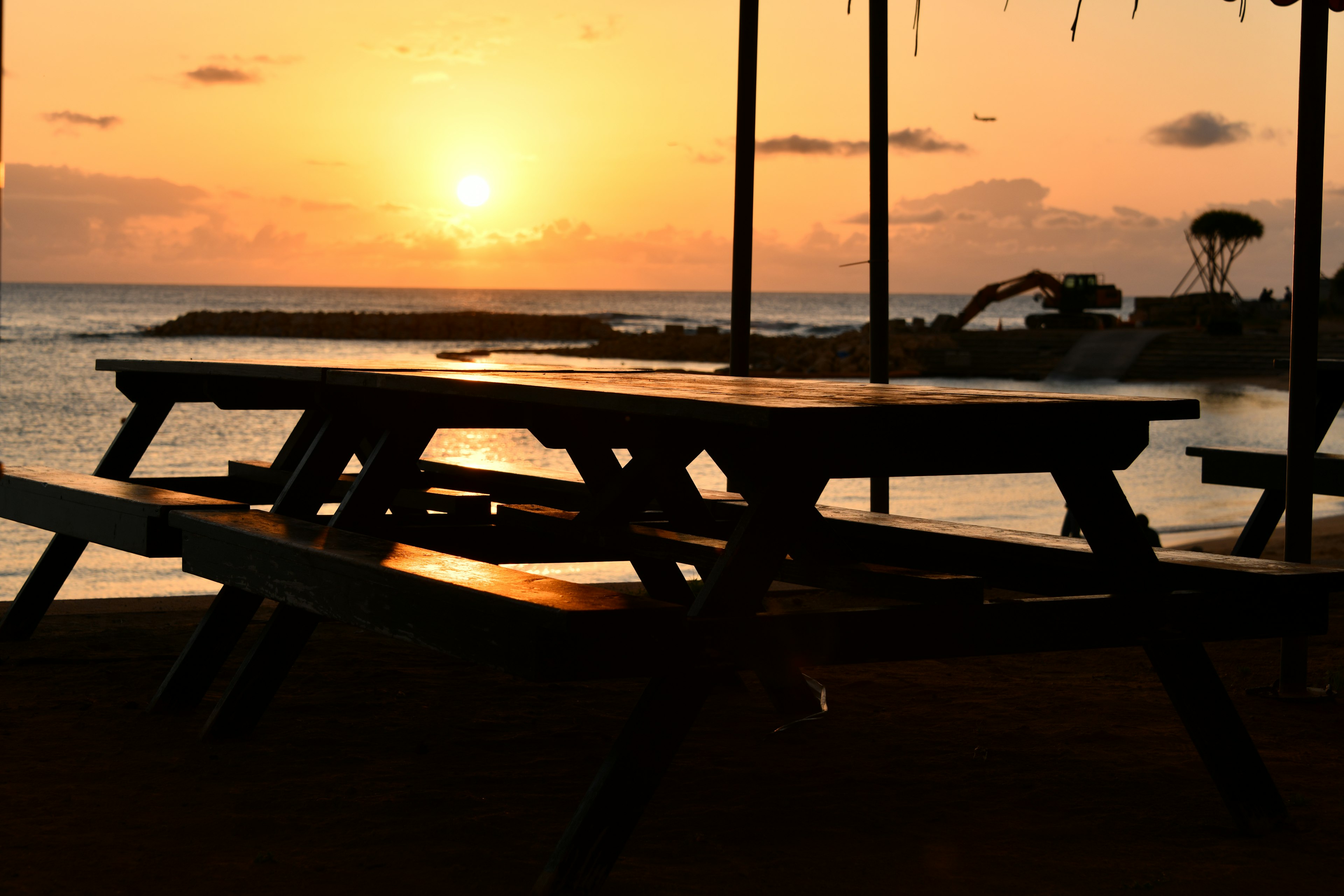 Silueta de mesas de picnic en una playa durante el atardecer