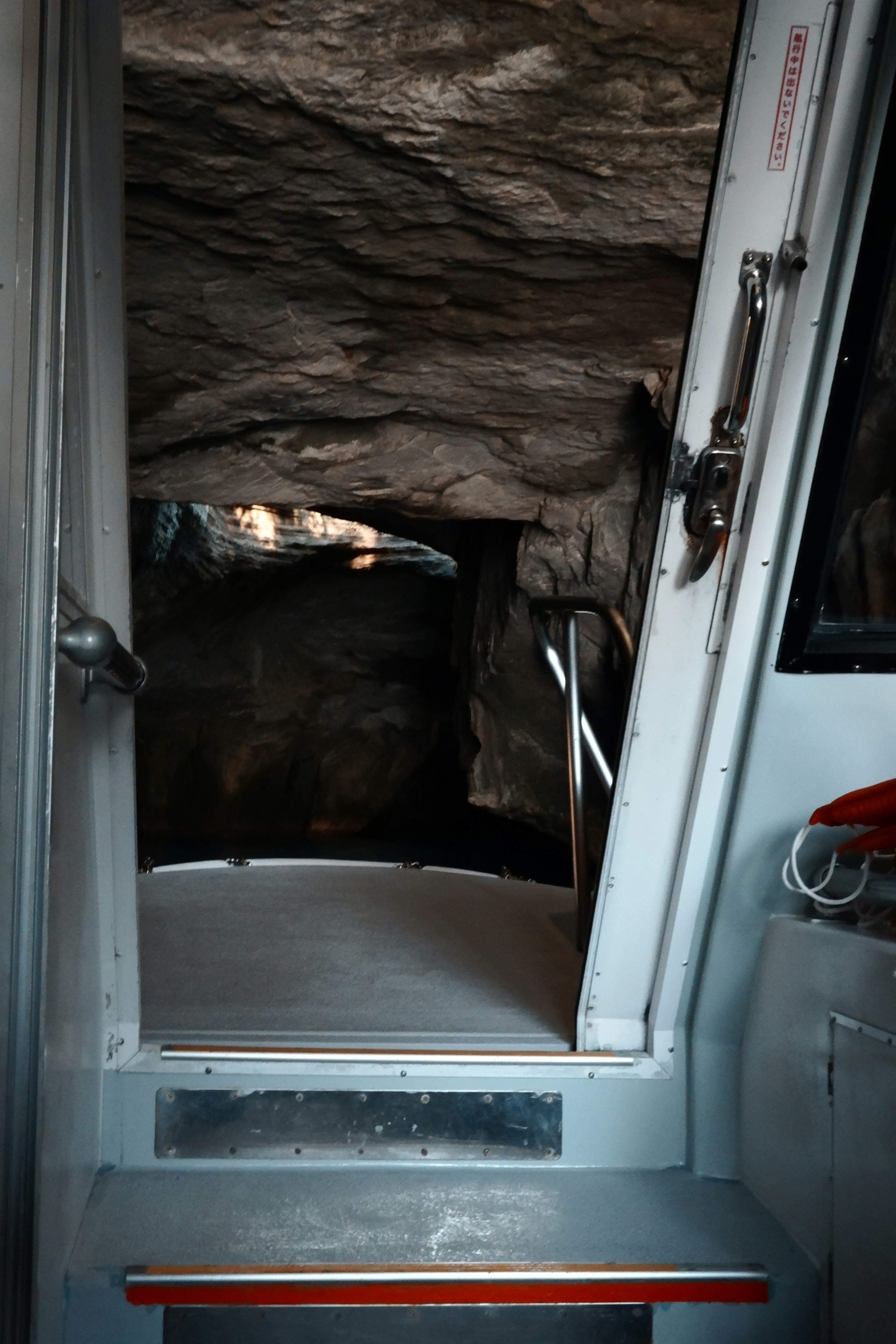 Image montrant une porte ouverte menant à une grotte avec des rochers environnants