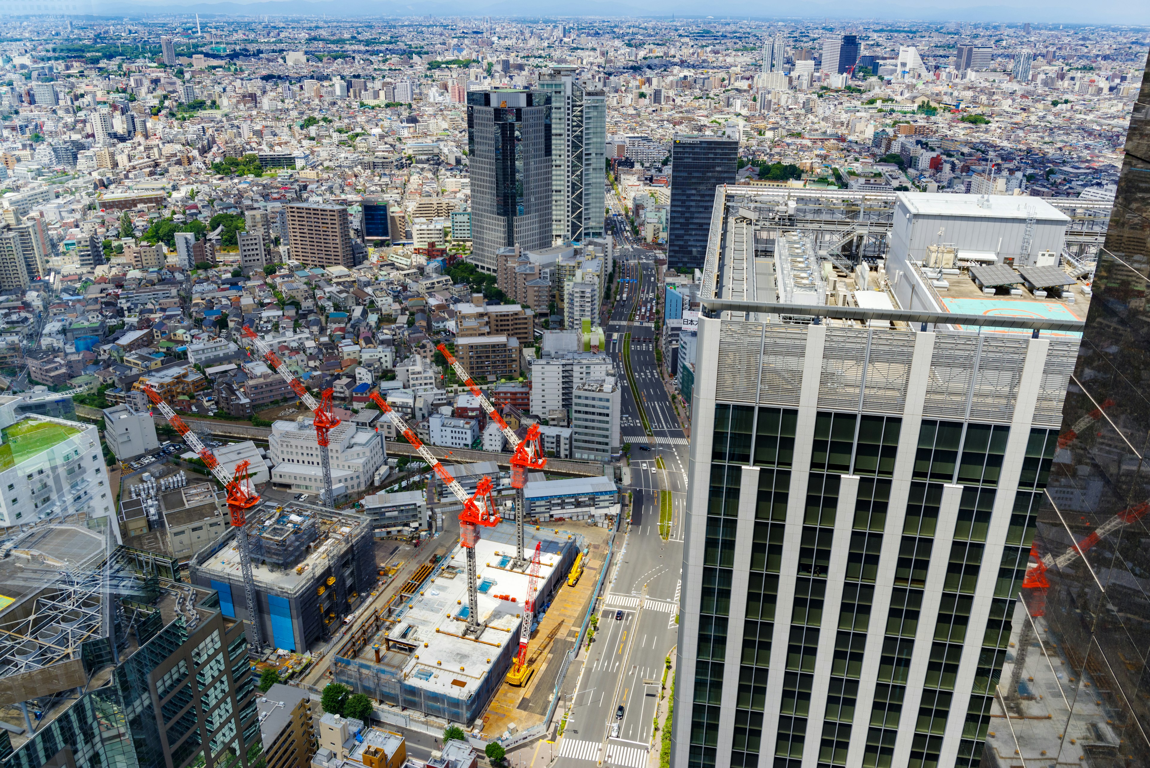 Aerial view of a cityscape featuring construction cranes and modern buildings