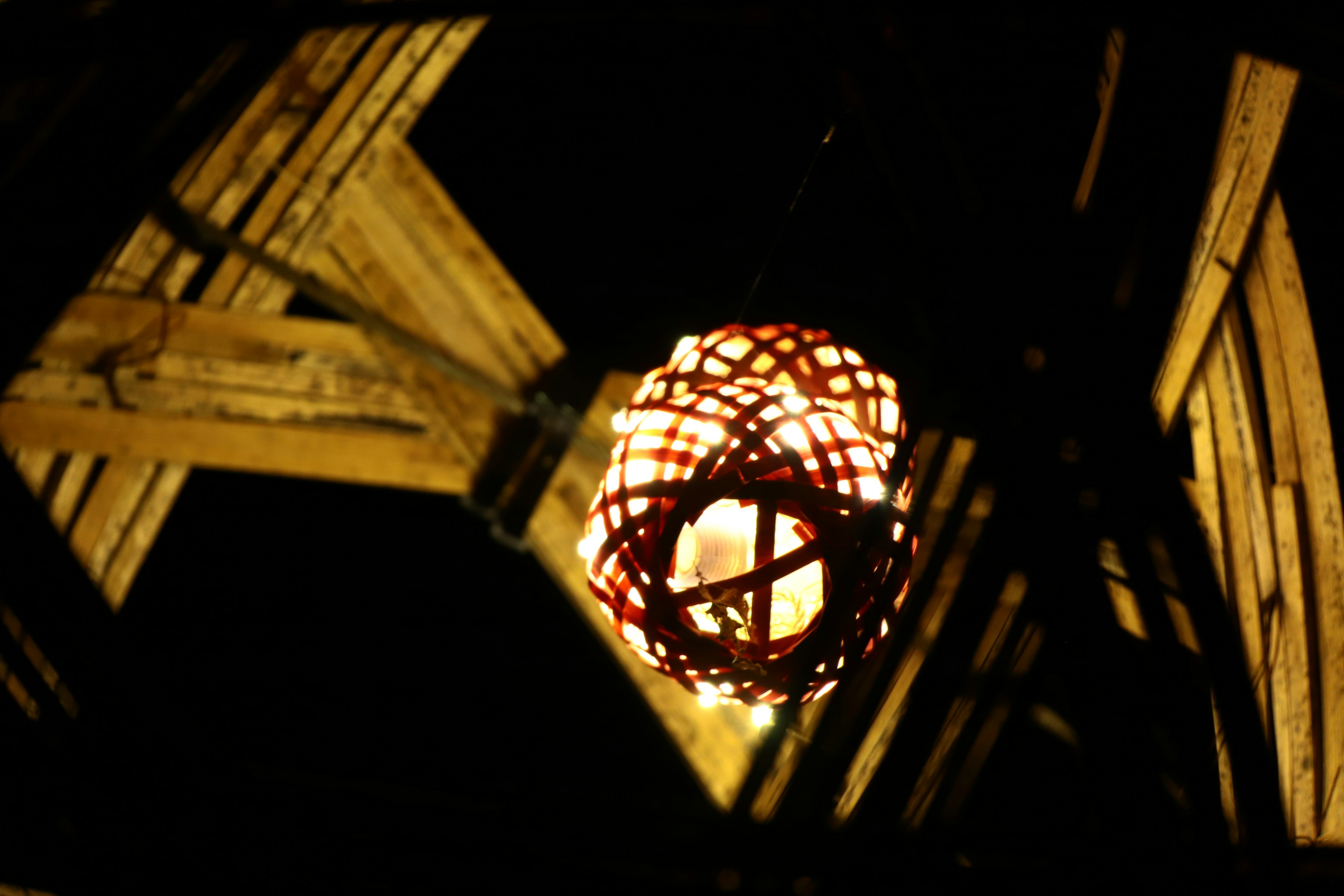 Una luz de linterna colgando entre vigas de madera iluminando el entorno