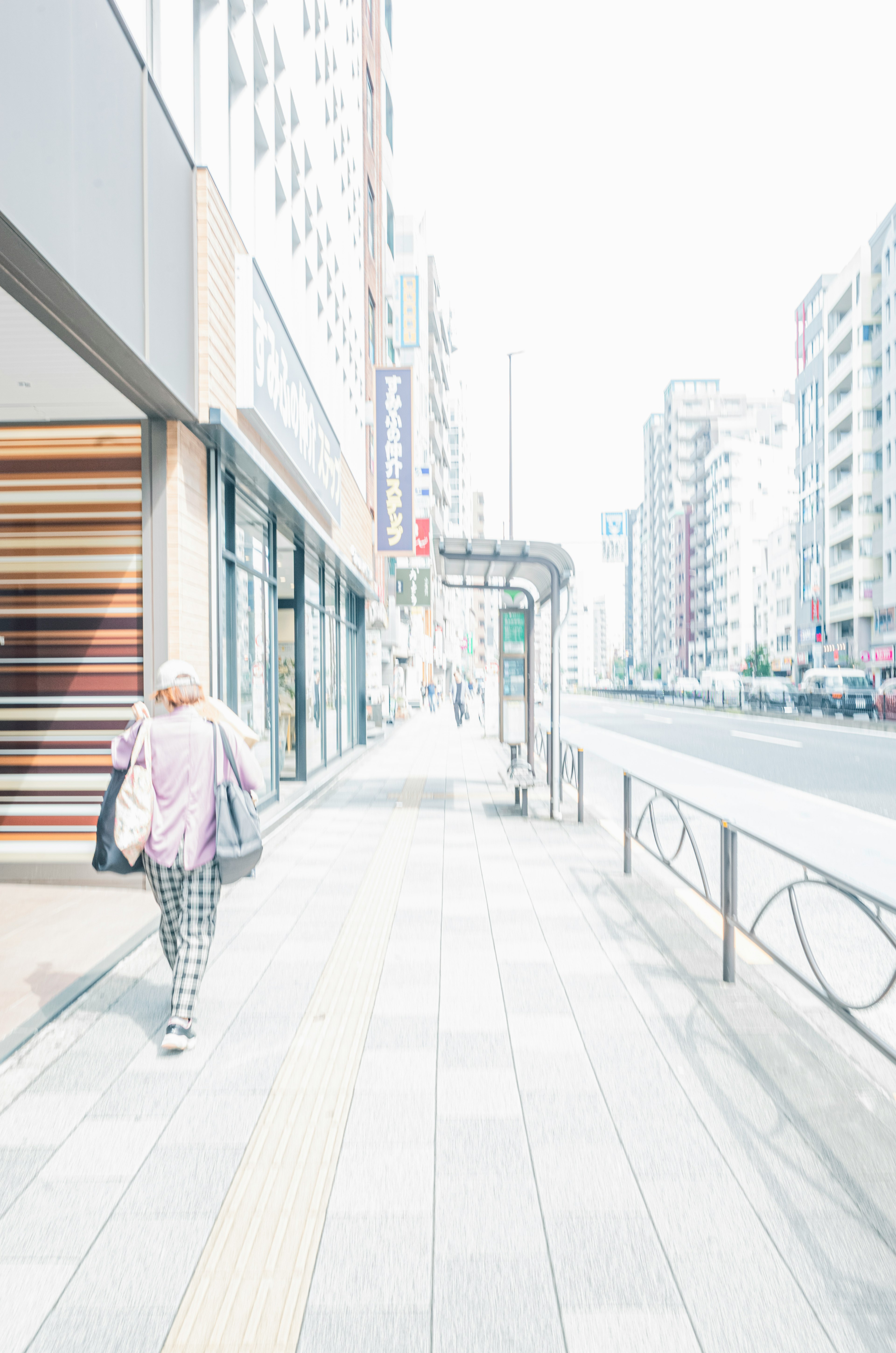 薄明かりの中を歩く女性の後ろ姿 都市の街並みと歩道