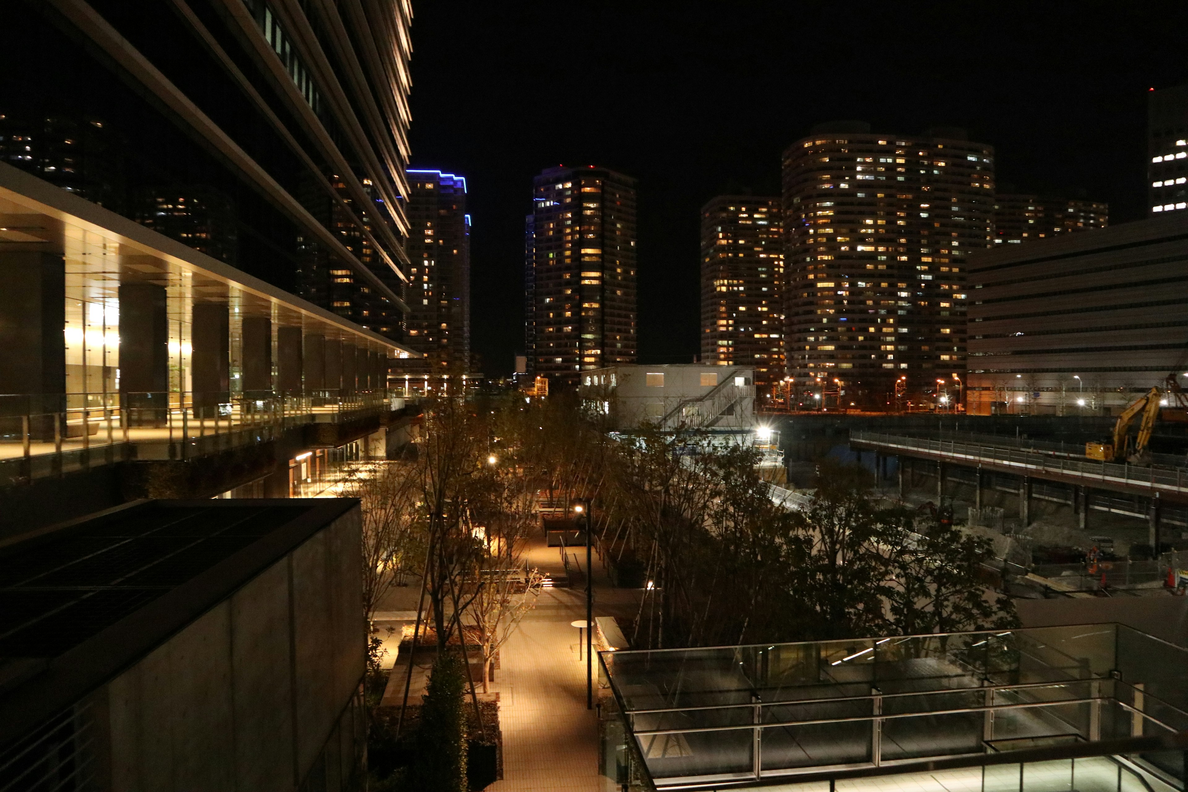 Night cityscape with illuminated buildings, lit streets, construction site