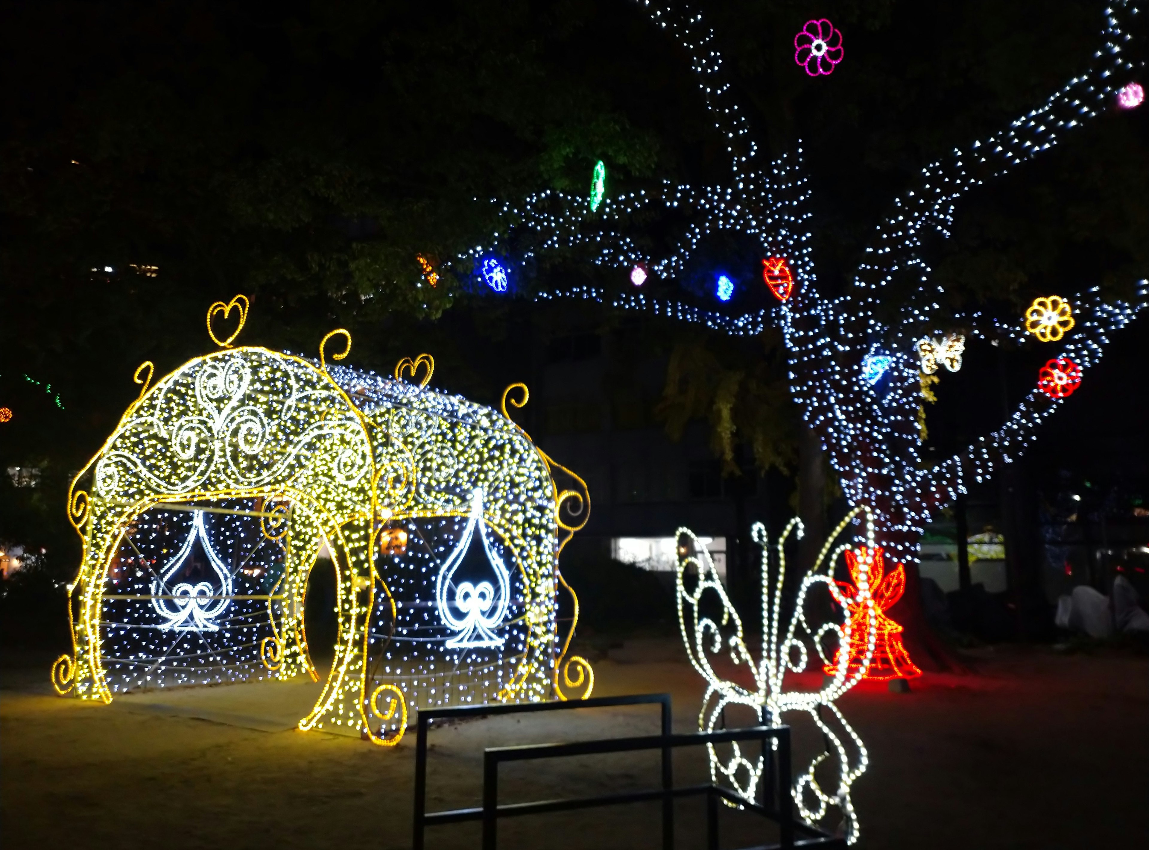 Illuminated butterfly and decorative hut display in a night park