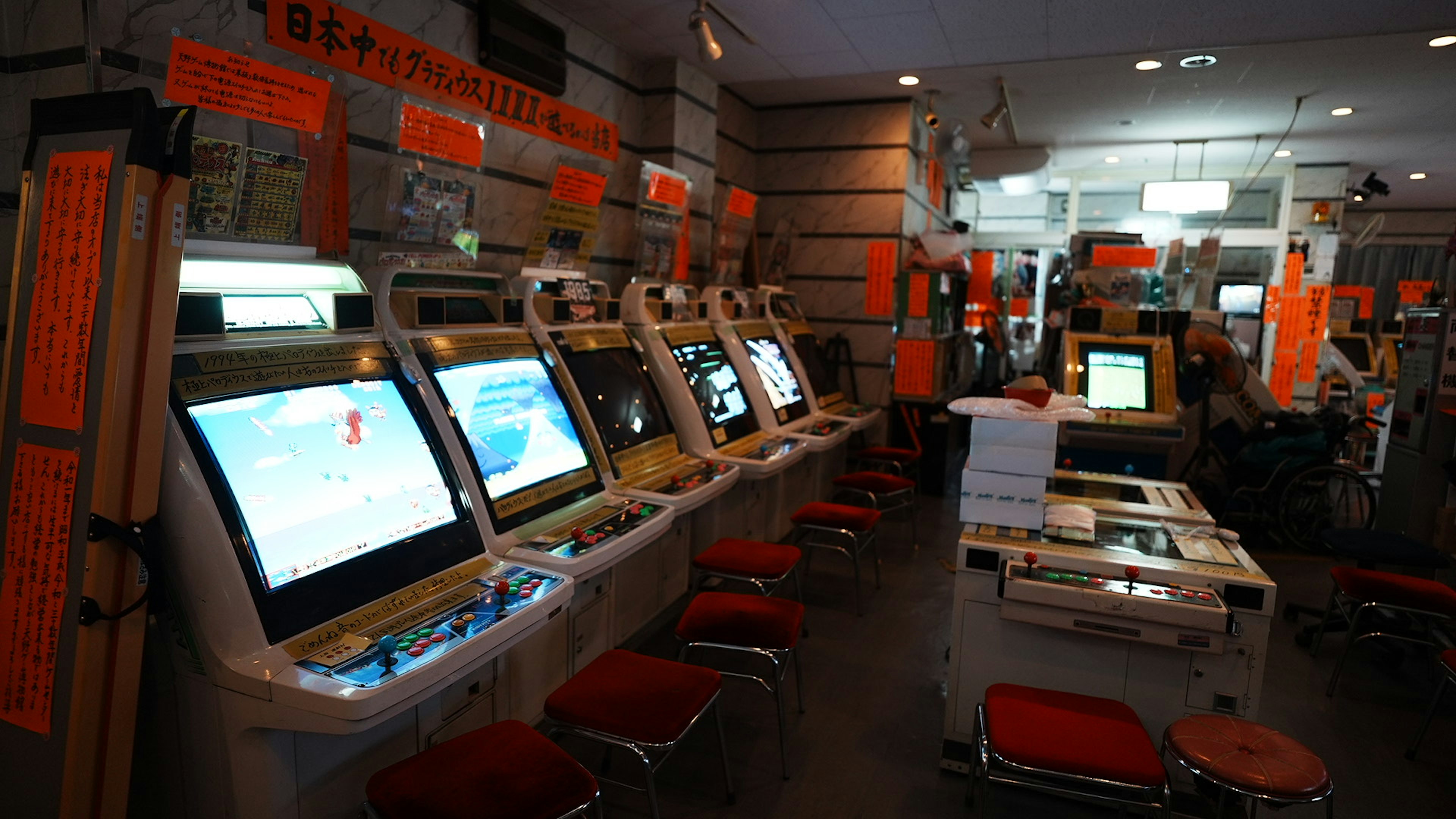 Intérieur d'un centre de jeux avec plusieurs machines de jeu et une signalisation orange