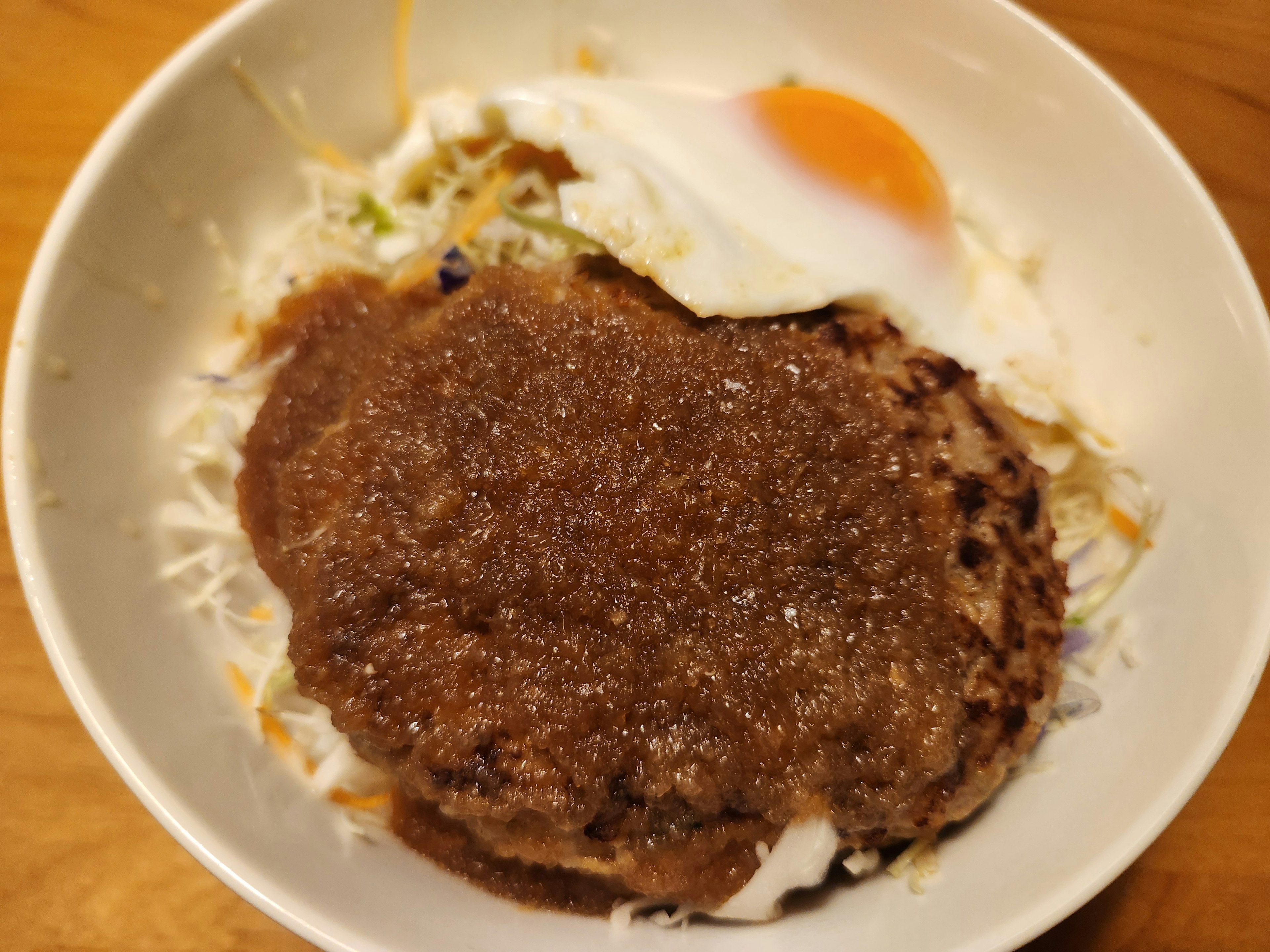 A bowl of rice topped with a hamburger steak and a fried egg