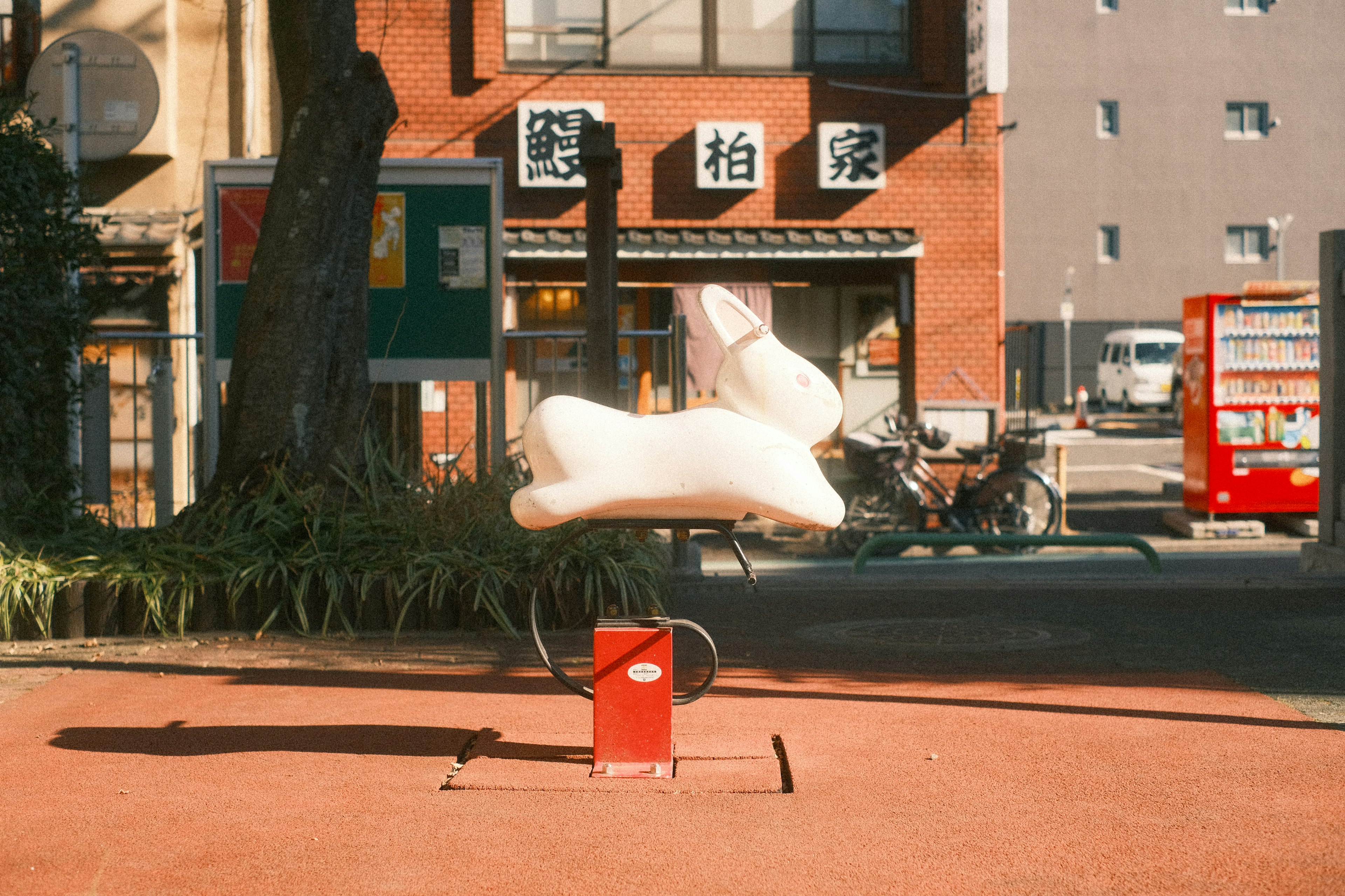 A floating white rabbit sculpture in a park with surrounding buildings