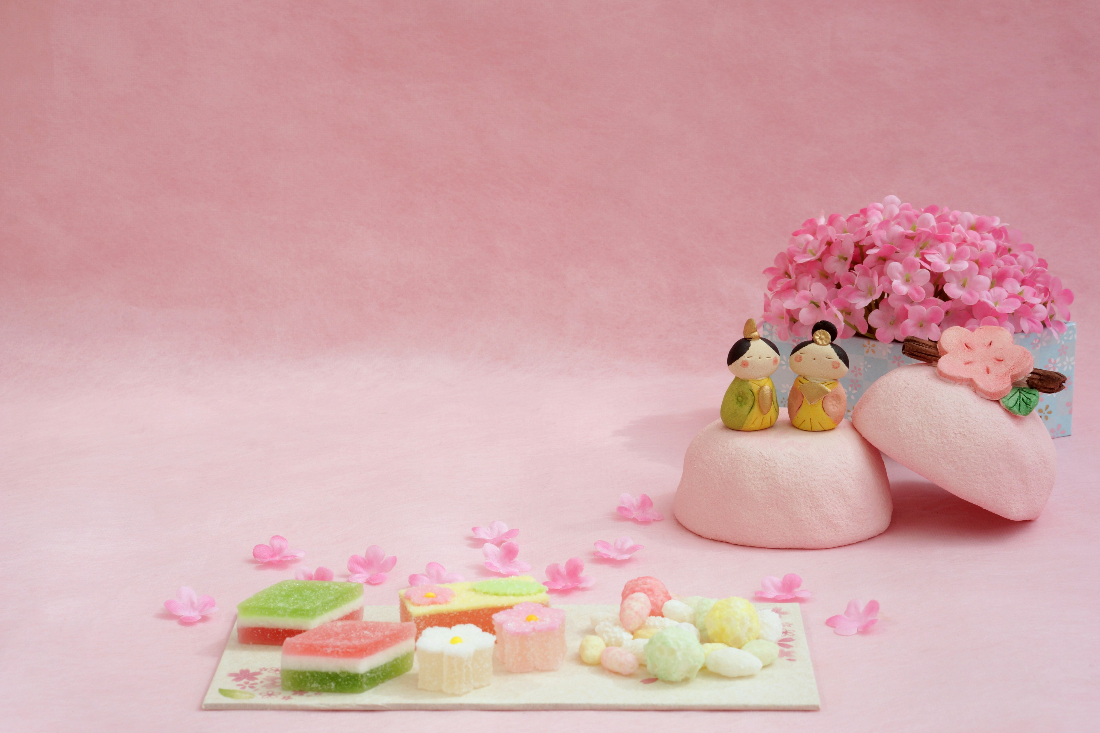 Imagen con fondo rosa y flores de cerezo junto a dulces japoneses variados