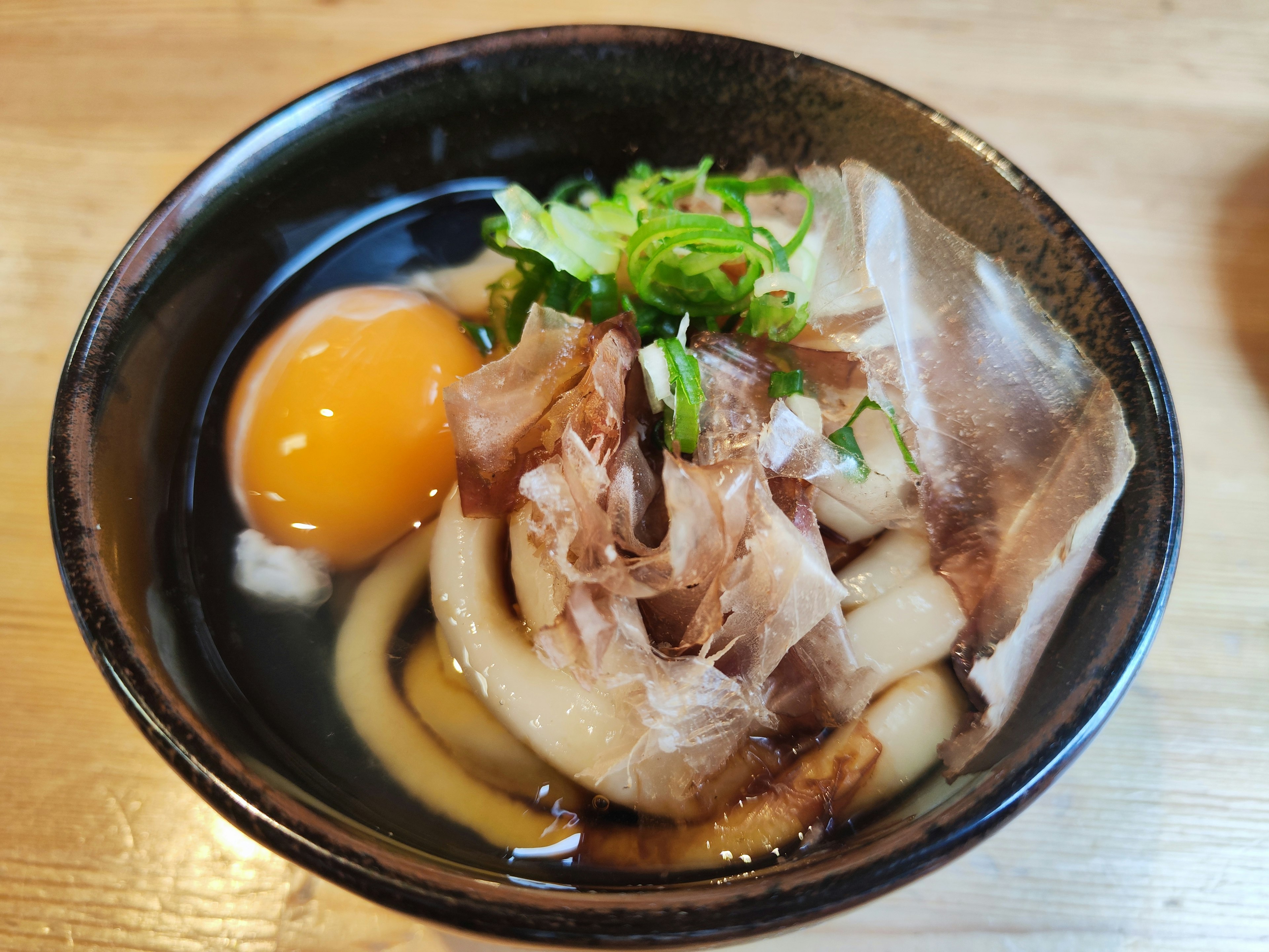 Bol de nouilles udon garni d'un œuf cru et d'oignons verts