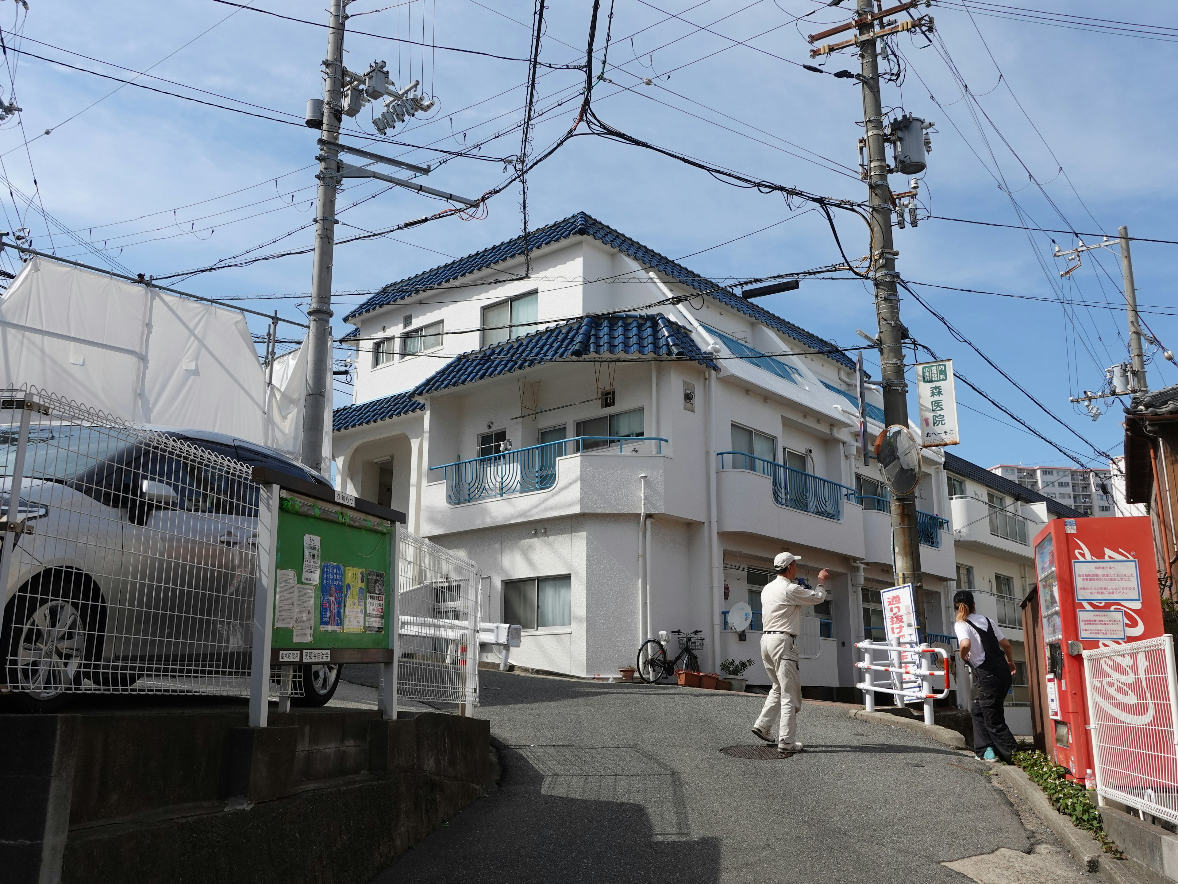 White building at a street corner under a blue sky with pedestrians