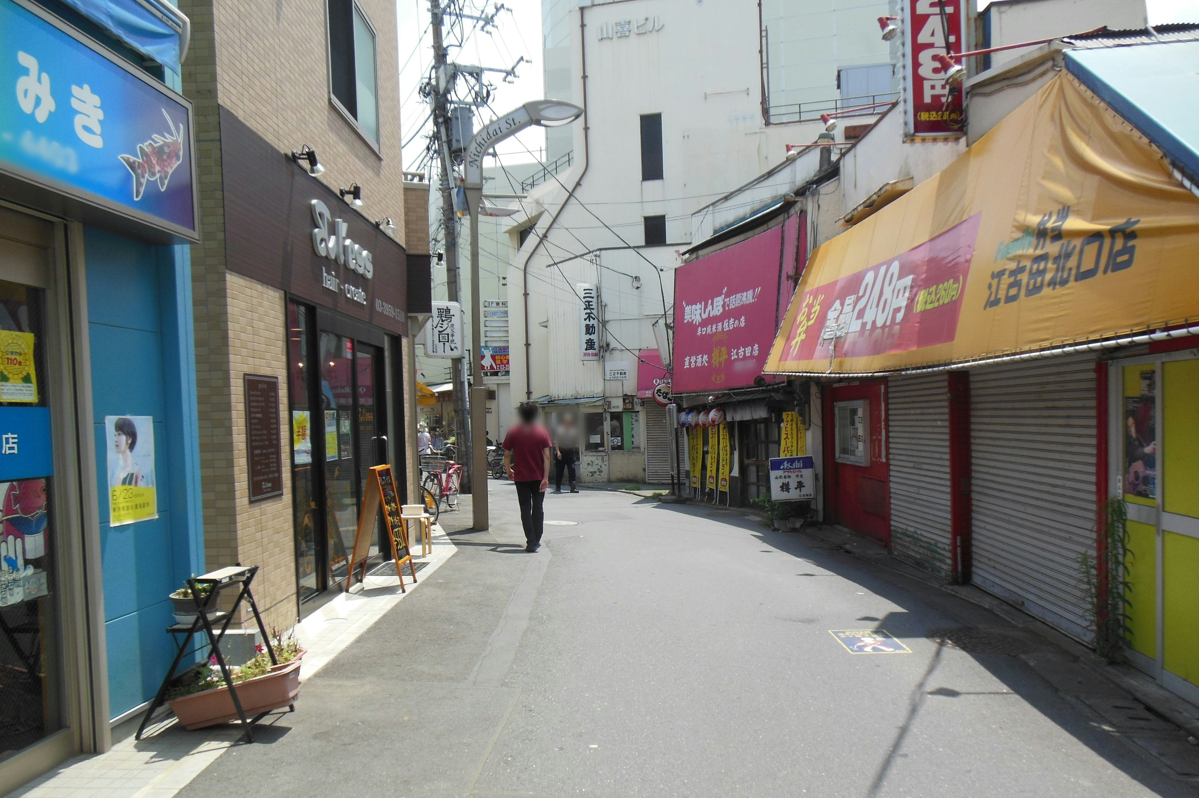 Callejón estrecho con tiendas y una persona caminando