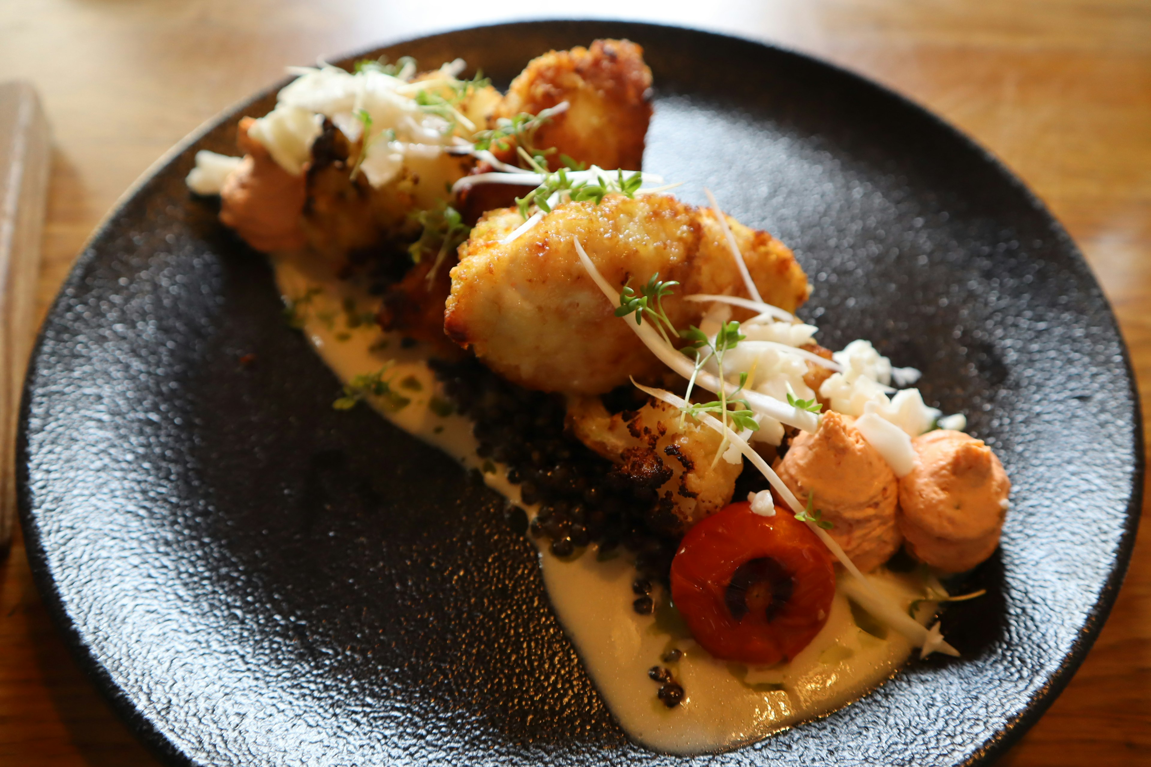 Un plato con salmón y verduras en un plato negro