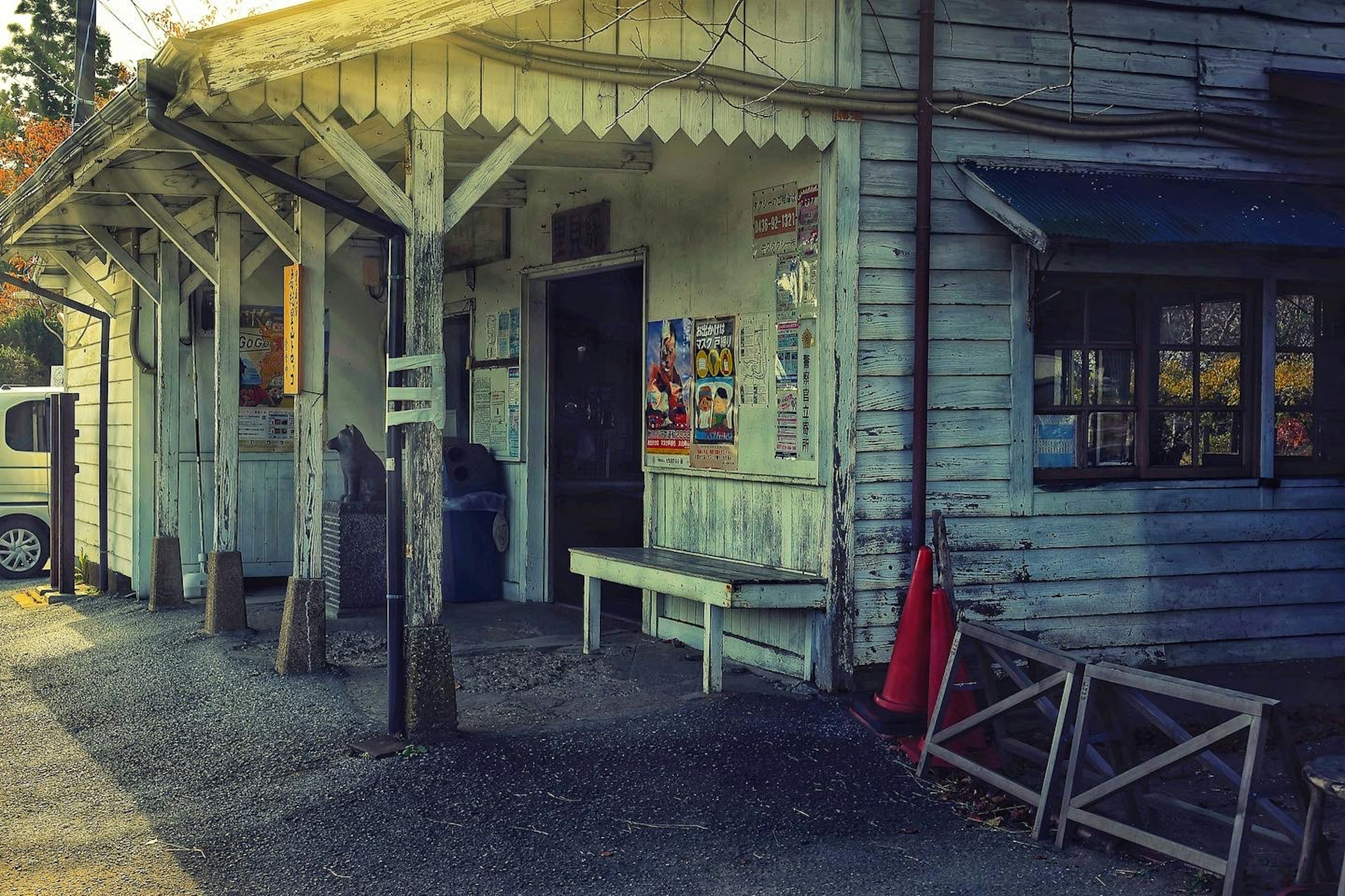 Exterior of an old wooden building with a white roof and posters on the walls