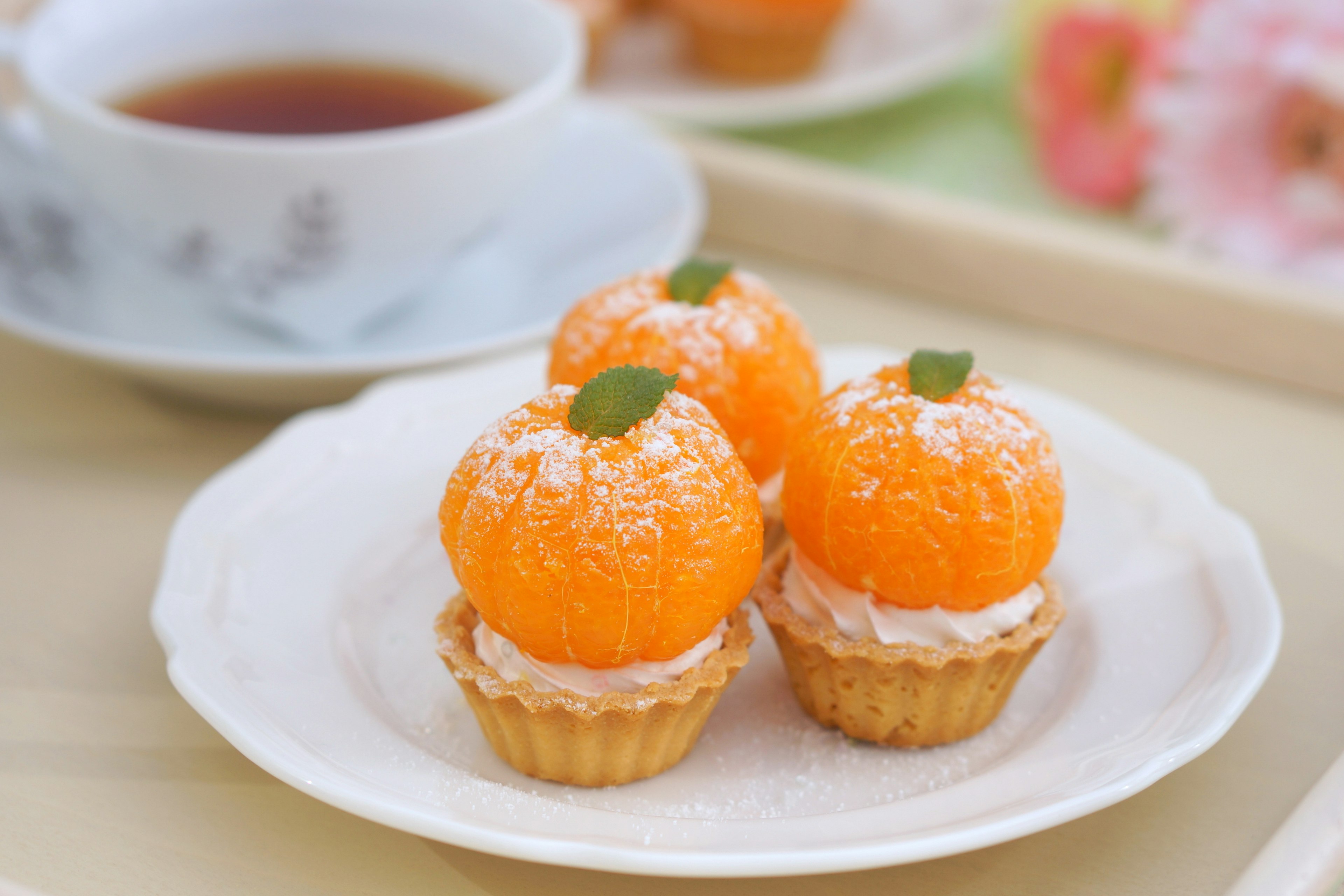 Cupcakes topped with orange desserts and a cup of tea