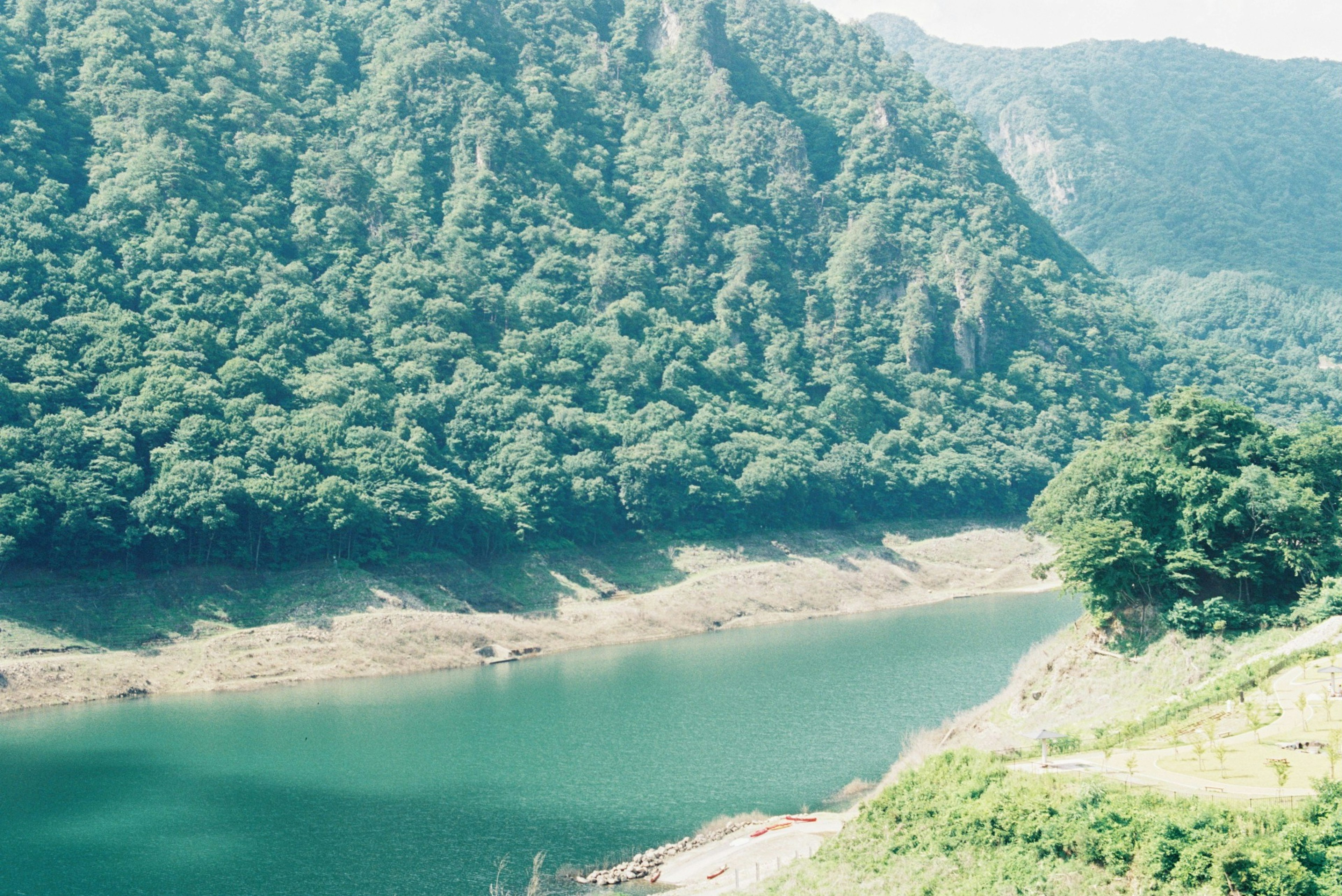 Danau tenang dikelilingi pegunungan hijau subur