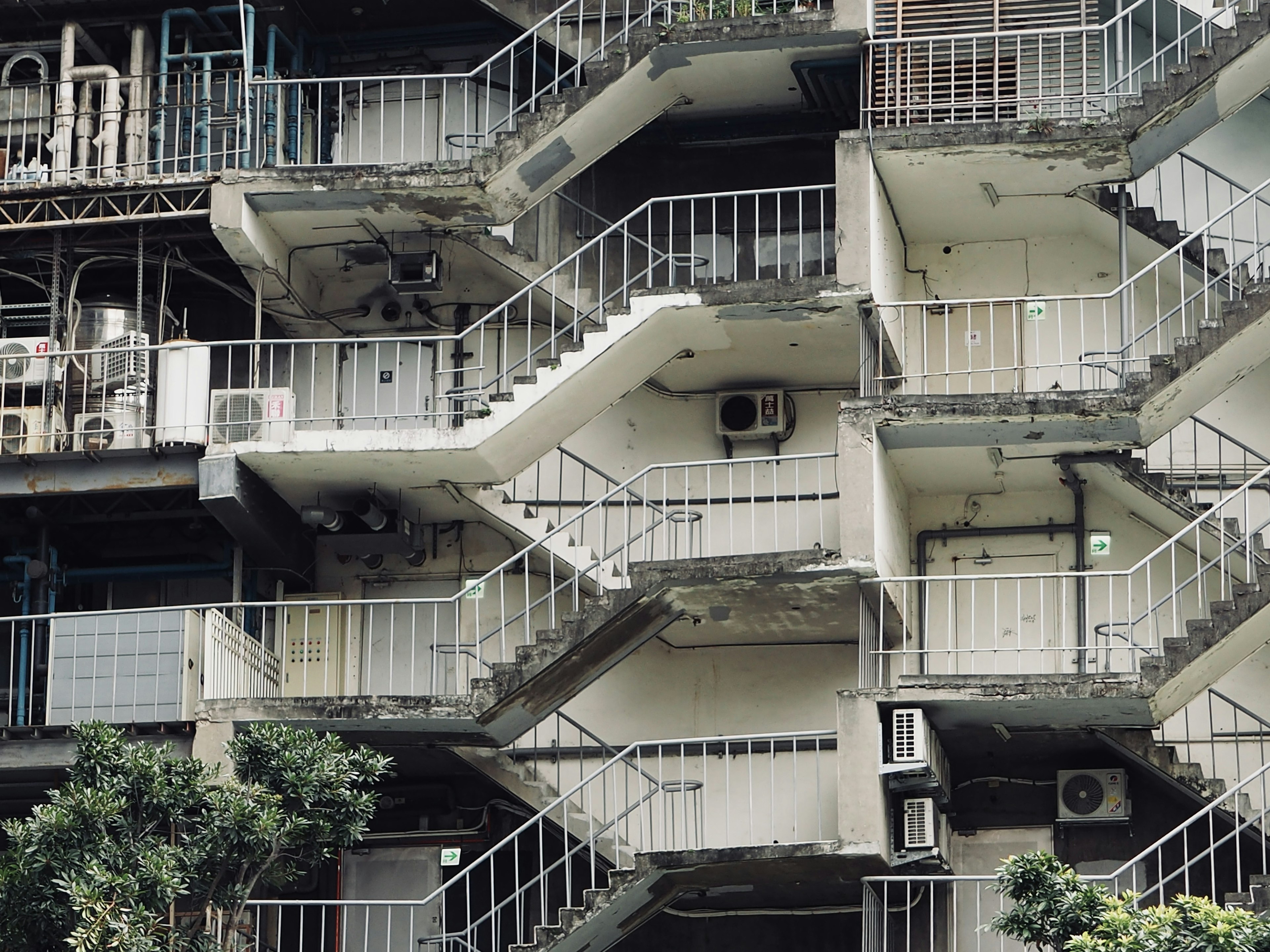 Exterior de un edificio con escaleras distintivas varias escaleras y unidades de aire acondicionado visibles