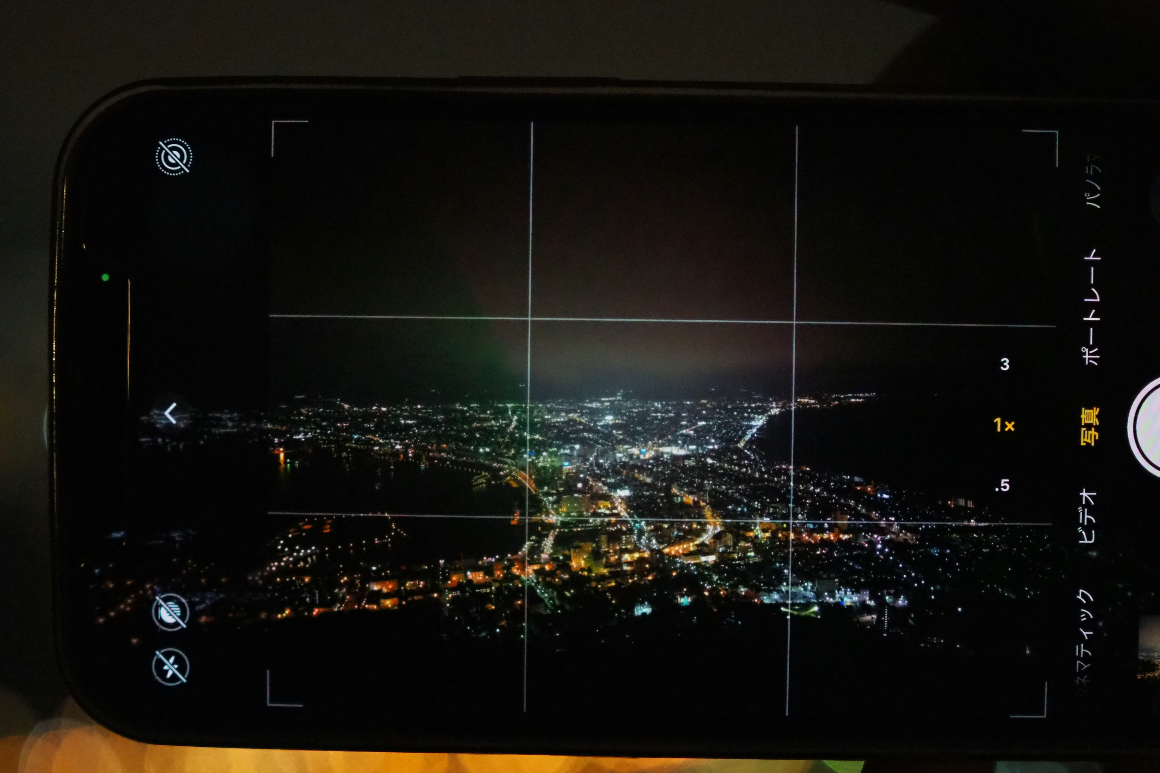 夜景を撮影したスマートフォンの画面が映る写真