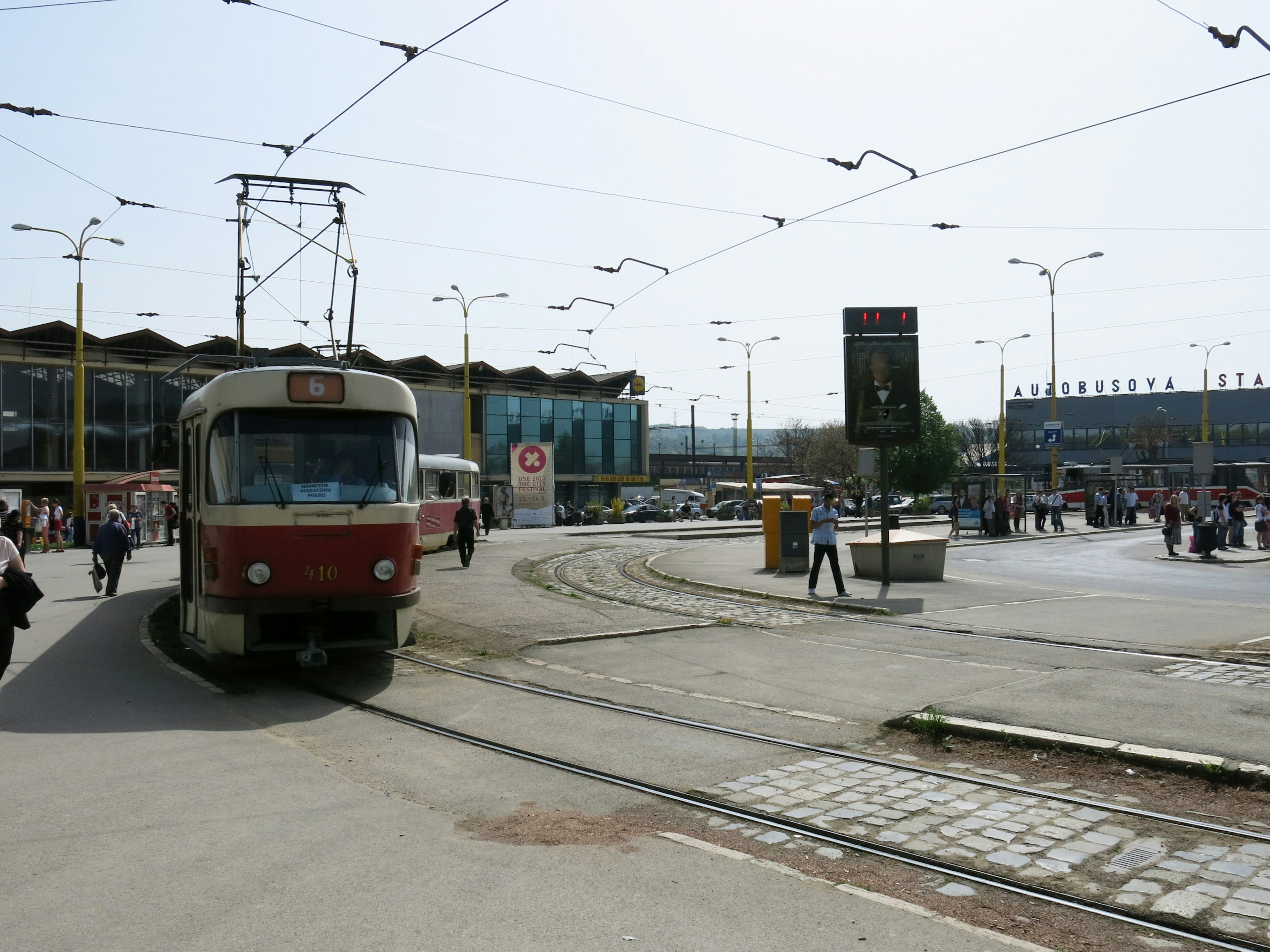 Straßenbahn fährt in einem belebten Bahnhofsplatz mit Menschen