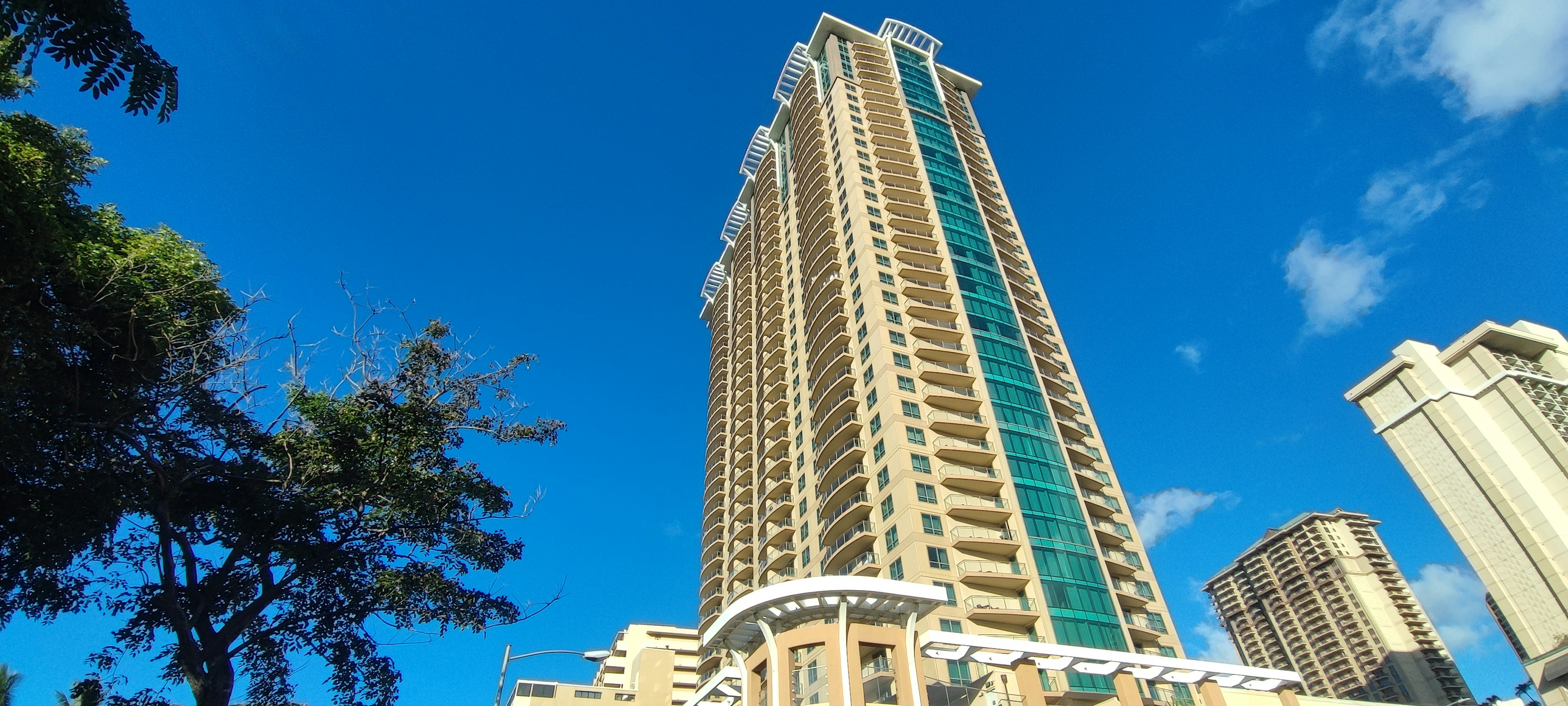 View of a tall building under a blue sky with green accents