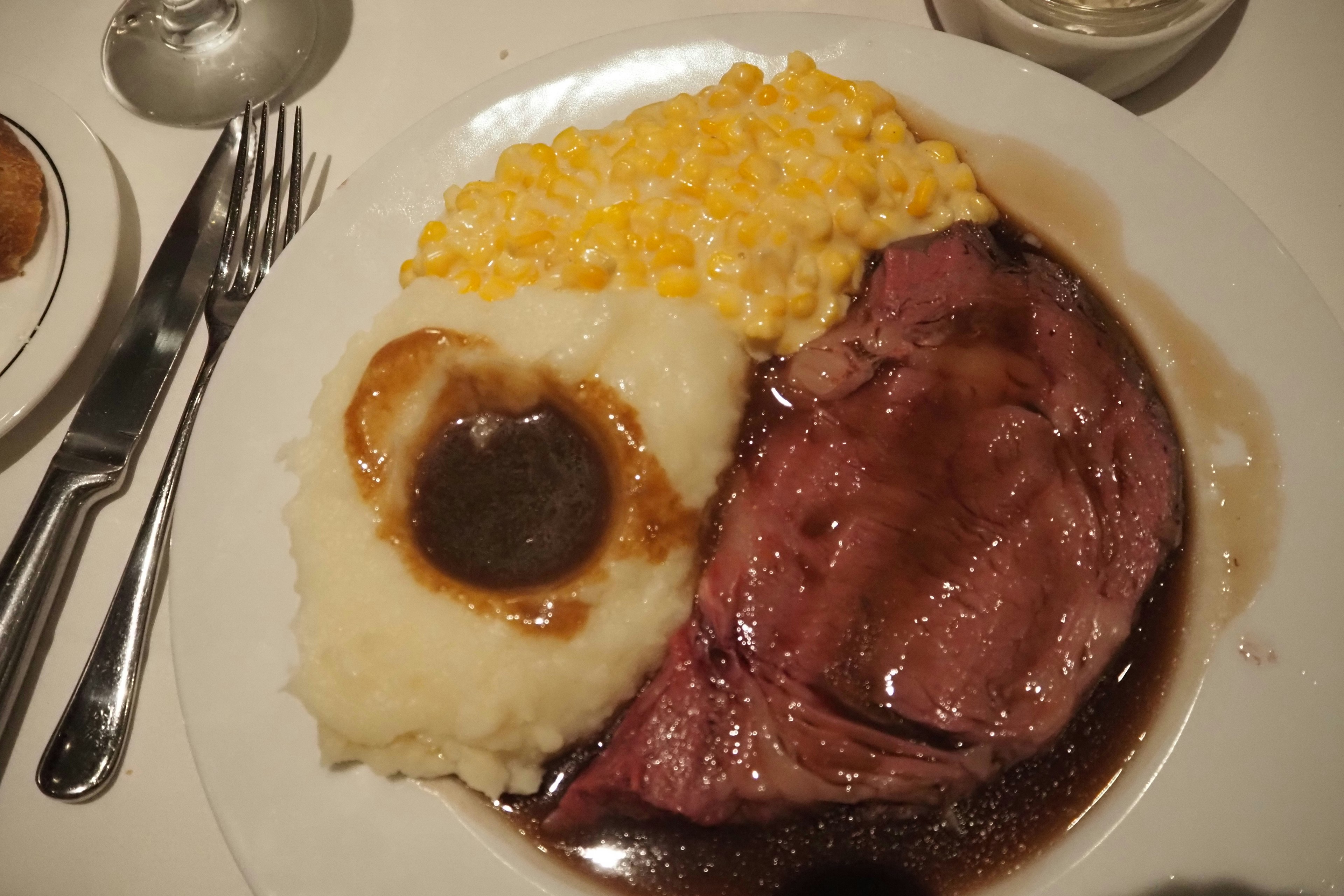 Un plato con carne asada, puré de papas y macarrones con queso