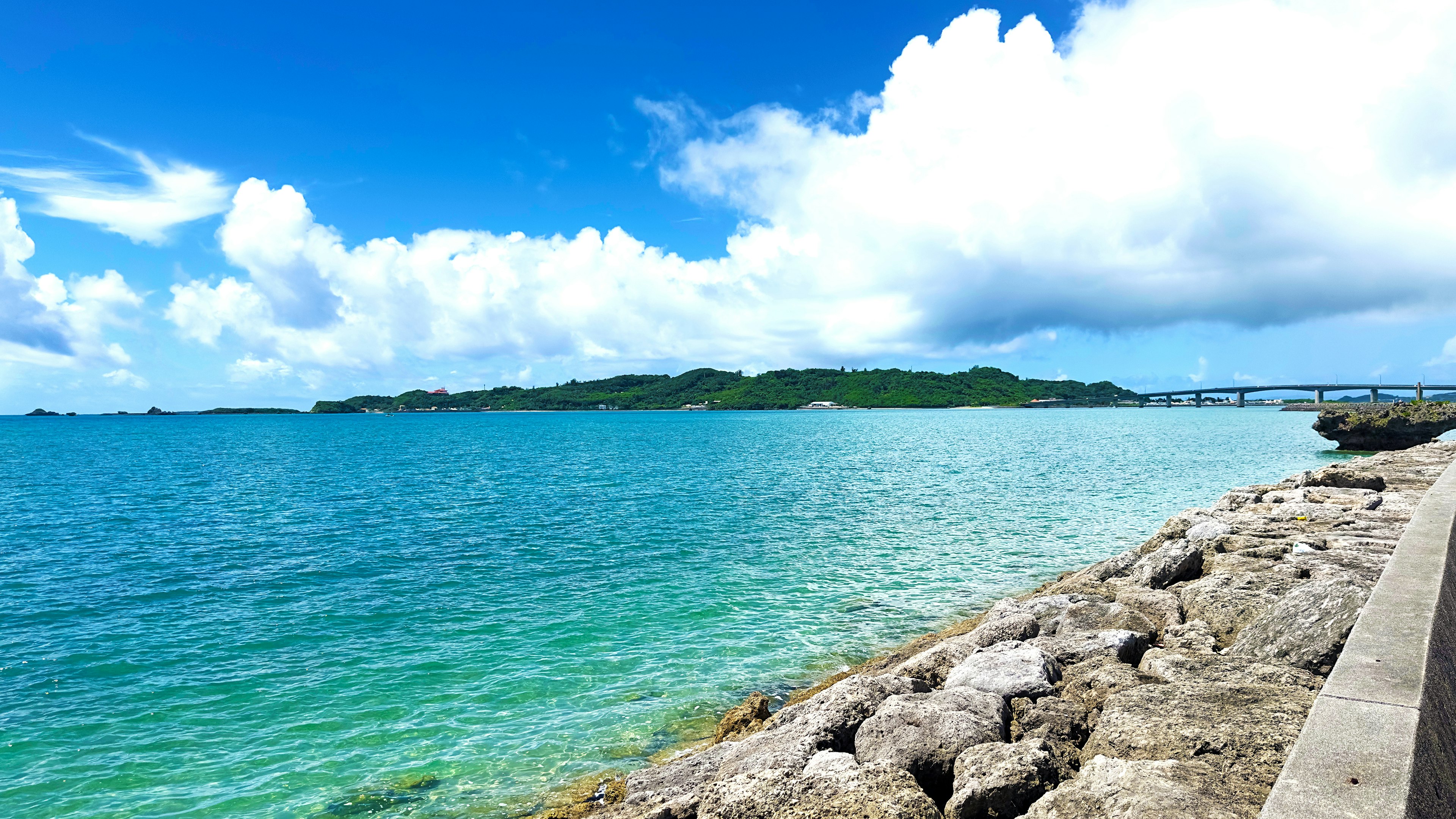 Beautiful seascape with blue water and white clouds rocky shore in the foreground