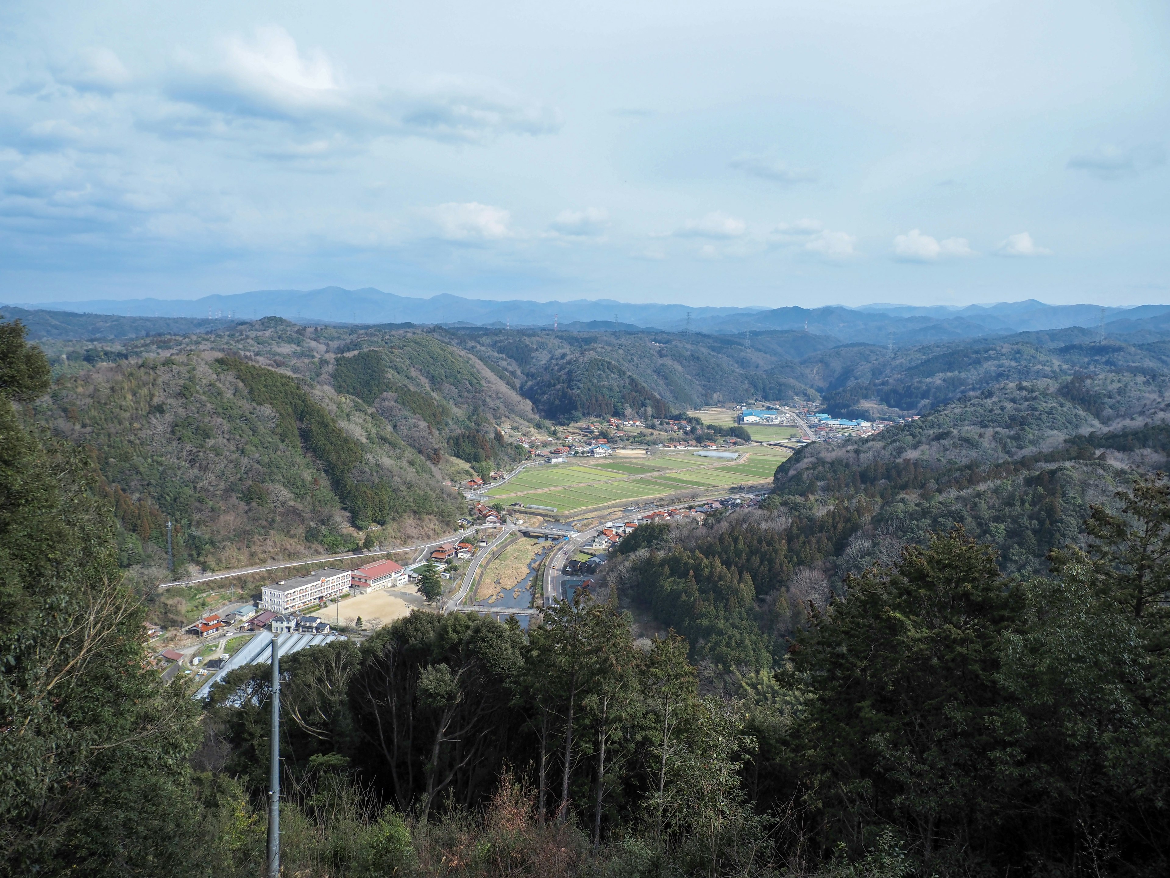 Scenic valley surrounded by mountains featuring green fields and small settlements