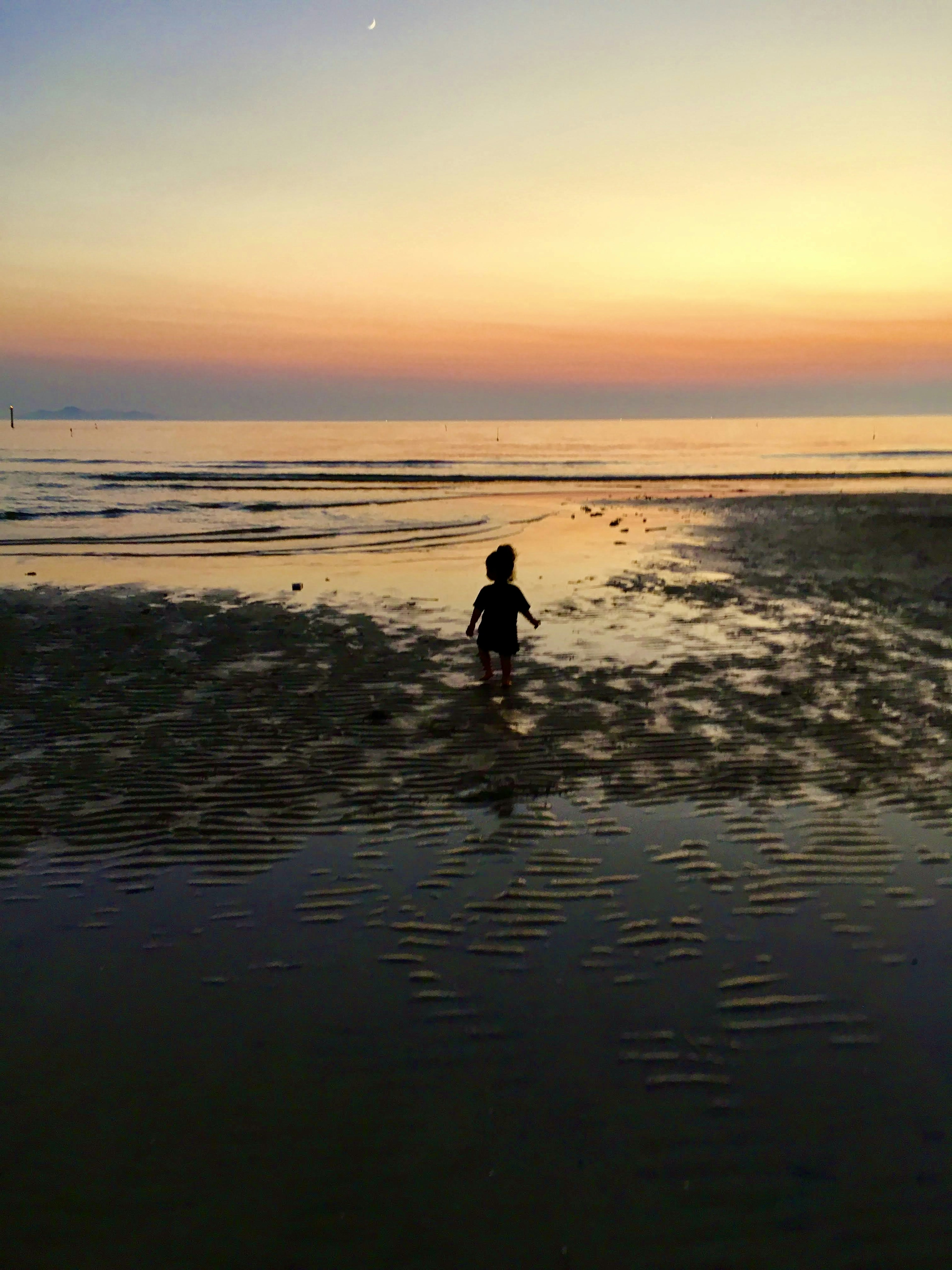 夕日を背景に海岸で遊ぶ子供のシルエット