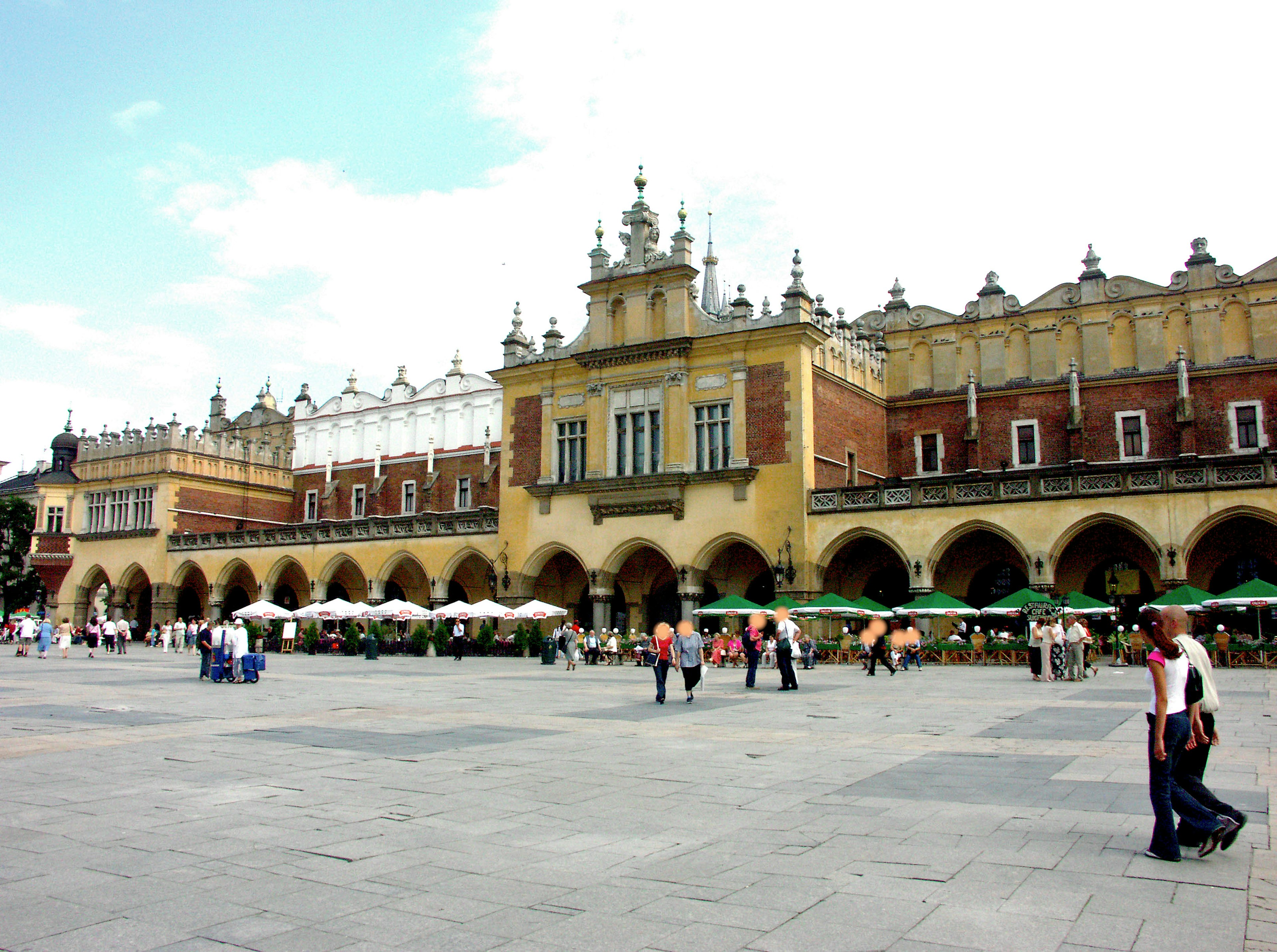 Extérieur d'un bâtiment historique sur la place de Cracovie avec des gens marchant