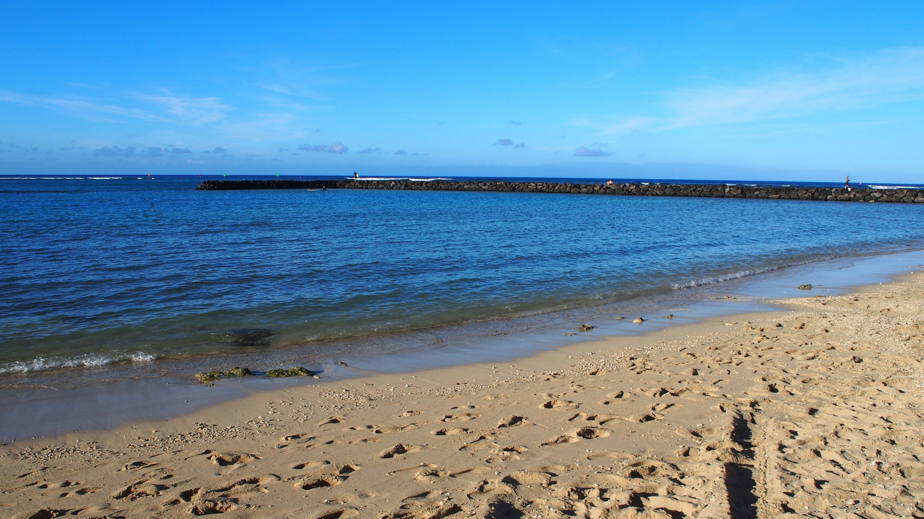 Pemandangan laut biru dan pantai berpasir di bawah langit cerah