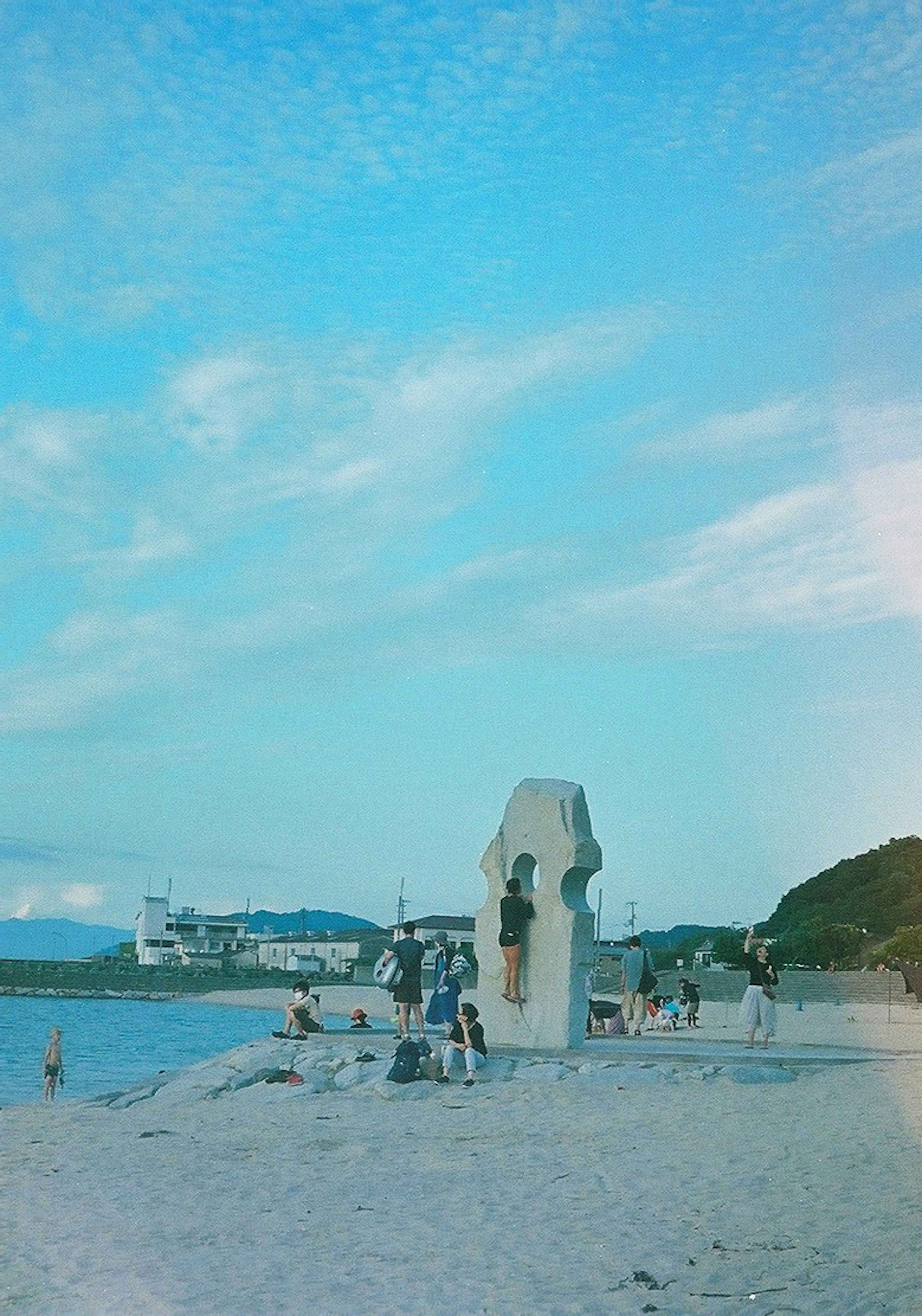 ทิวทัศน์ชายหาดที่มีประติมากรรมและผู้คนใต้ท้องฟ้าสีฟ้า