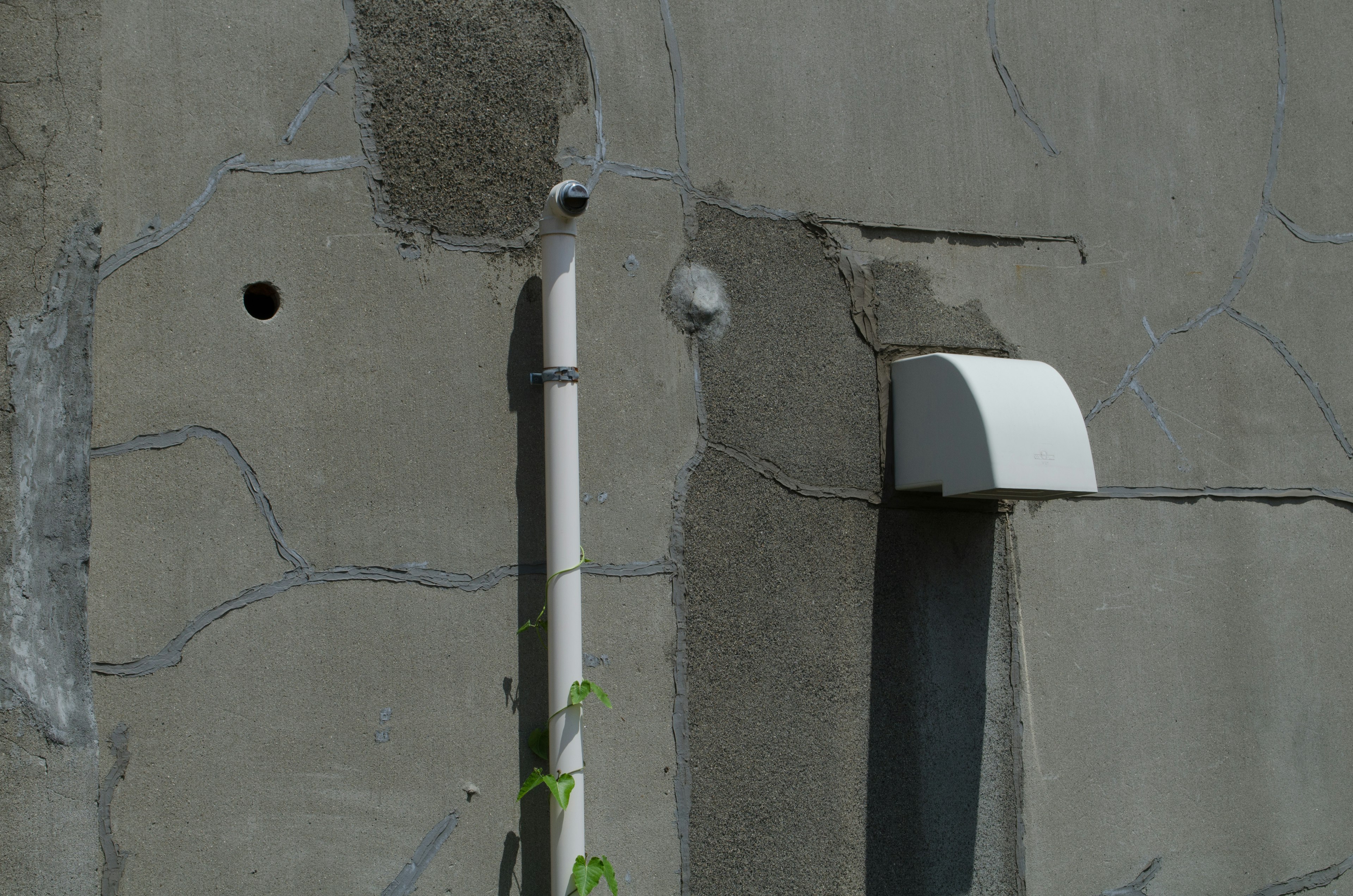 Gray wall featuring a pipe and structural holes