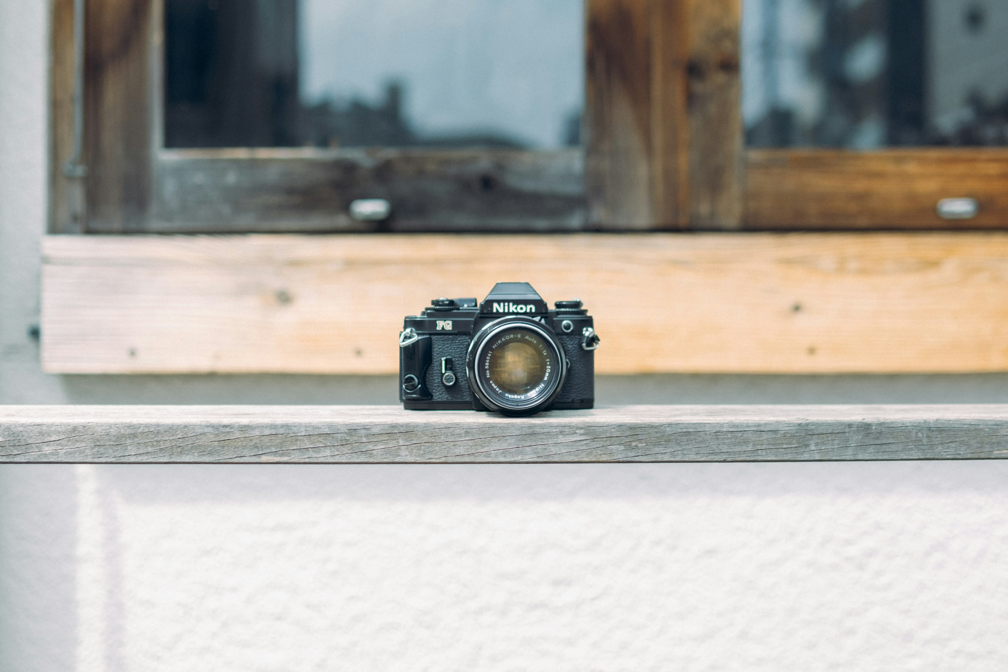 Una macchina fotografica posata su un tavolo vicino a una finestra