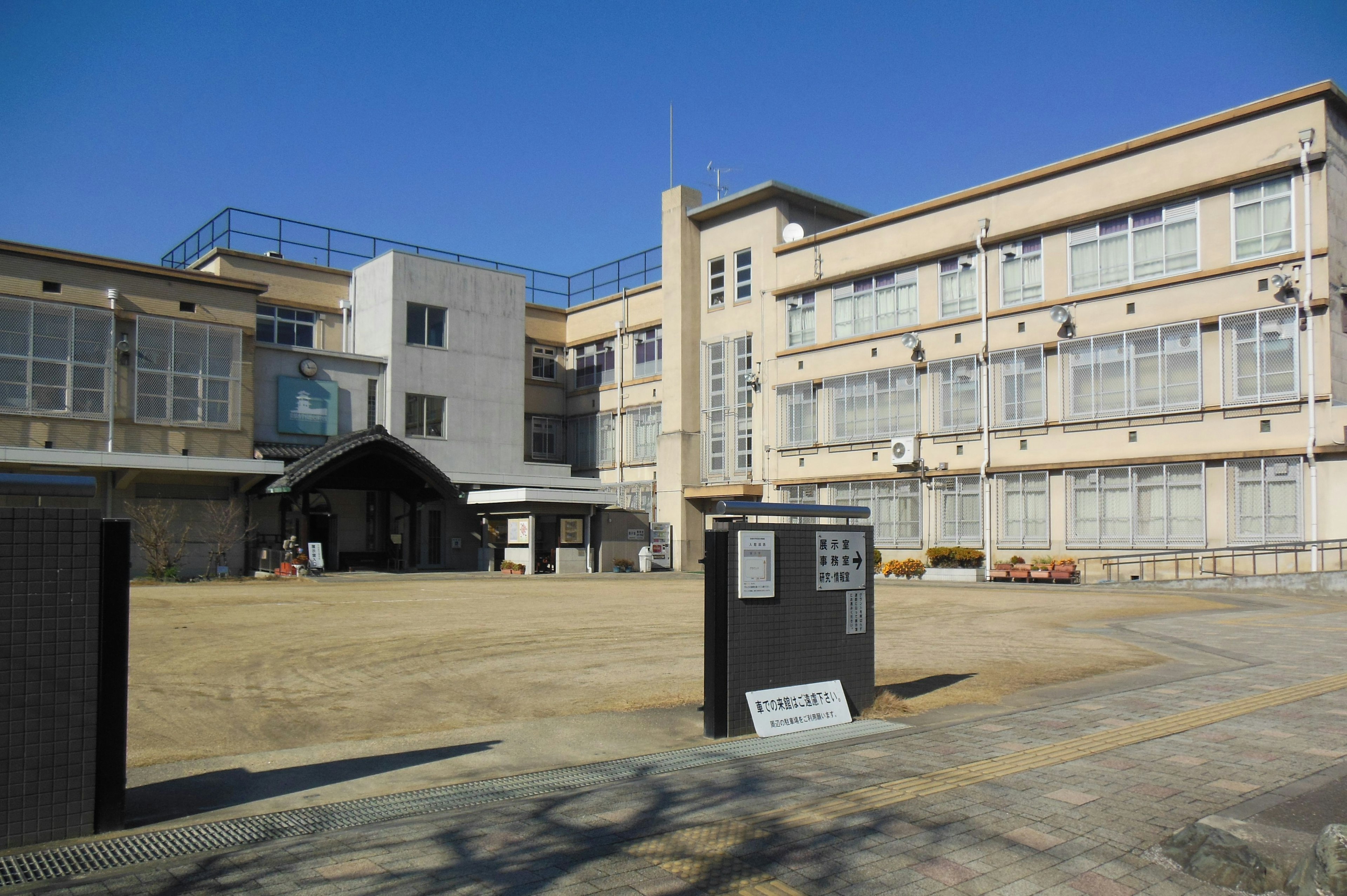 Edificio scolastico moderno con un cortile sotto un cielo blu chiaro