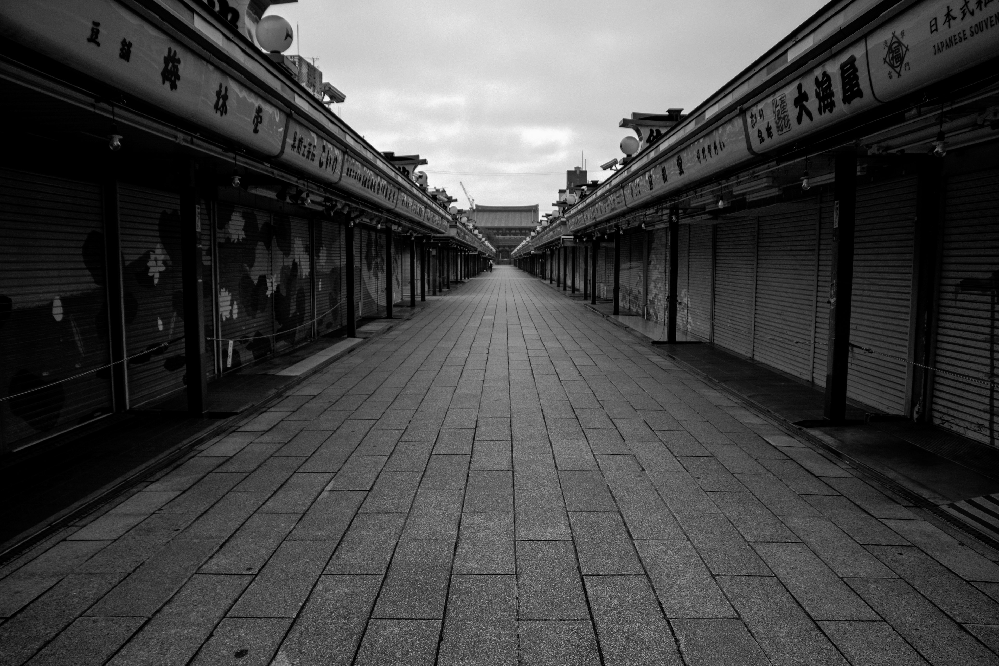 静かな商店街の通りが続くモノクロの風景